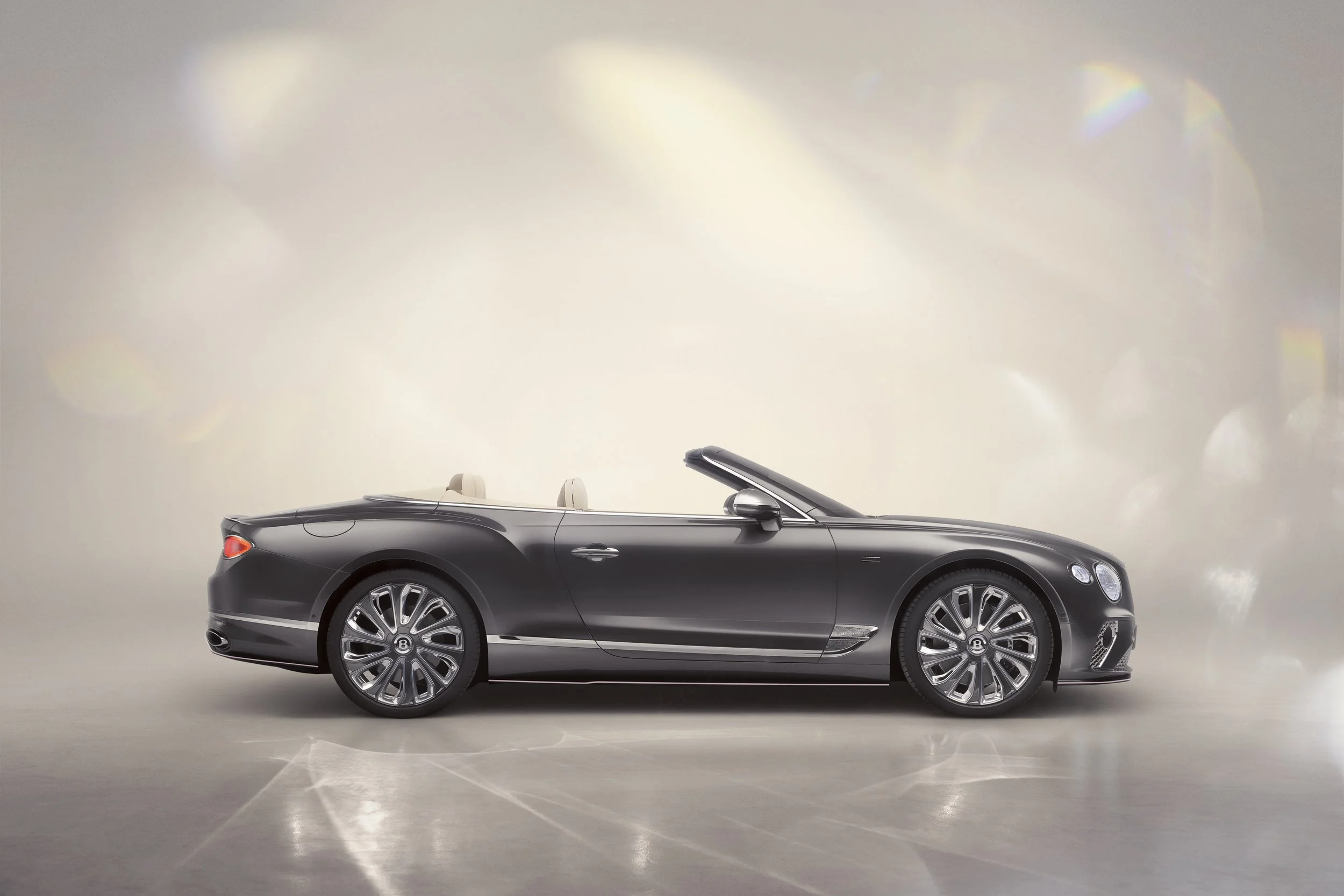 A sleek black convertible luxury car with beige interior and large multi-spoke alloy wheels, parked indoors against a neutral background.