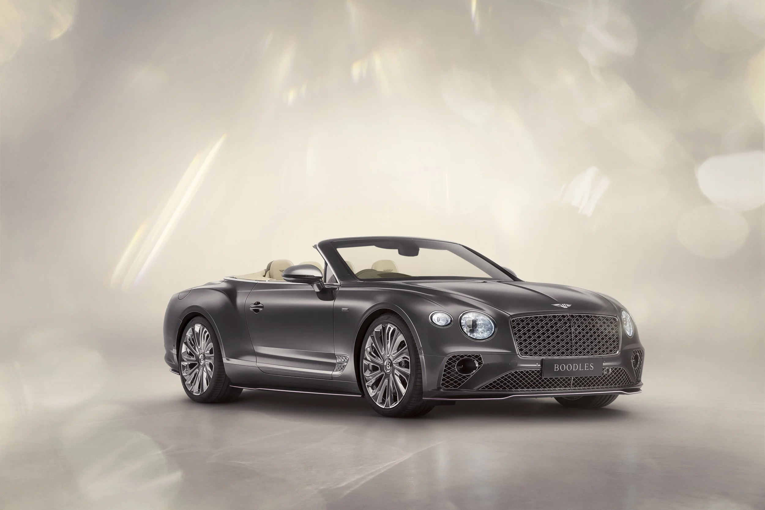 A black Bentley convertible car with a beige interior, displayed on a plain light-colored background.