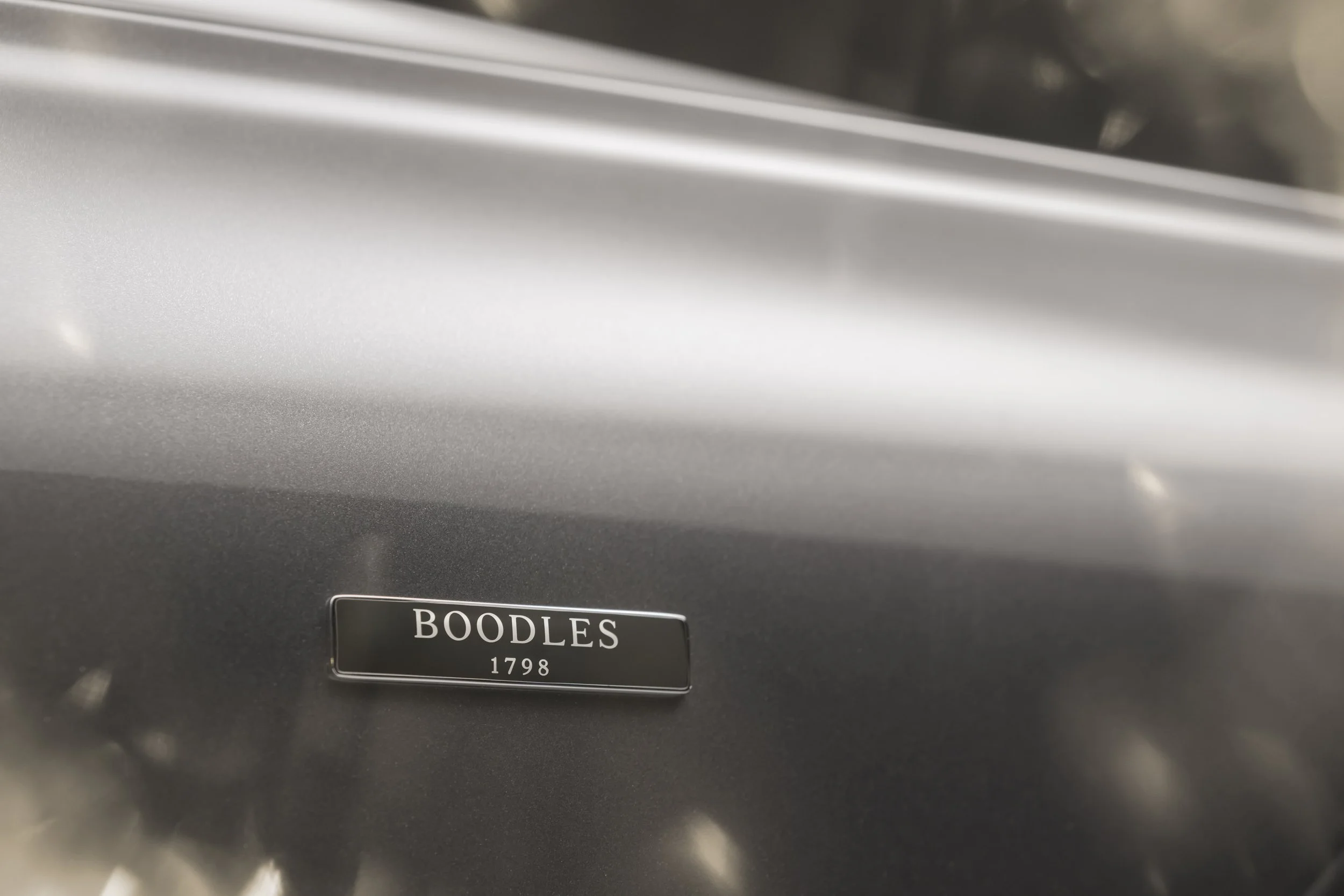 Close-up of a metallic gray surface with a black nameplate reading 'BOODLES 1798'.