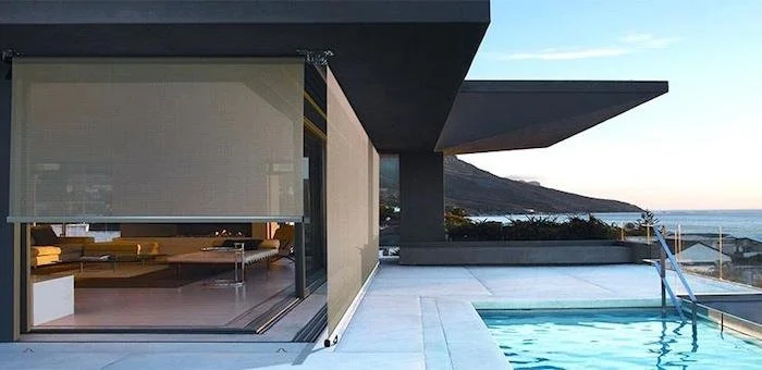 Modern house with an outdoor swimming pool and a view of the ocean and mountains in the background.