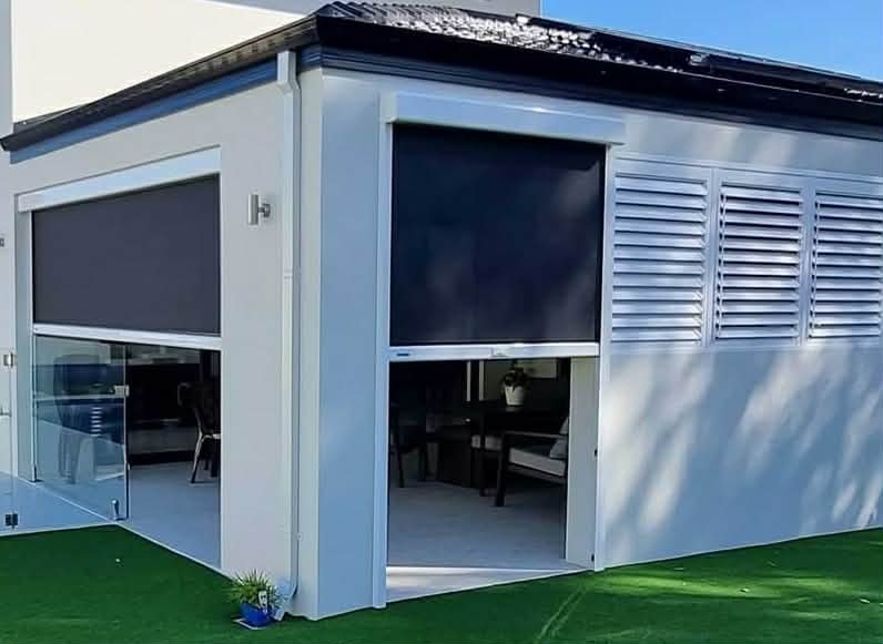 Exterior of a modern house with large windows and white siding, displaying a furnished patio area.