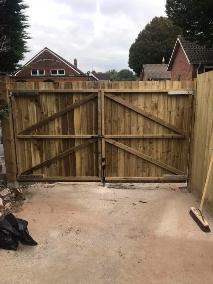 Newly built wooden gate with diagonal support beams, installed in a backyard.

