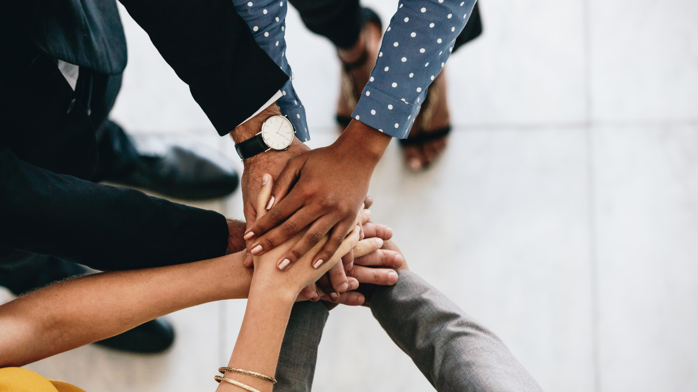 People stacking hands together in a show of teamwork or partnership.