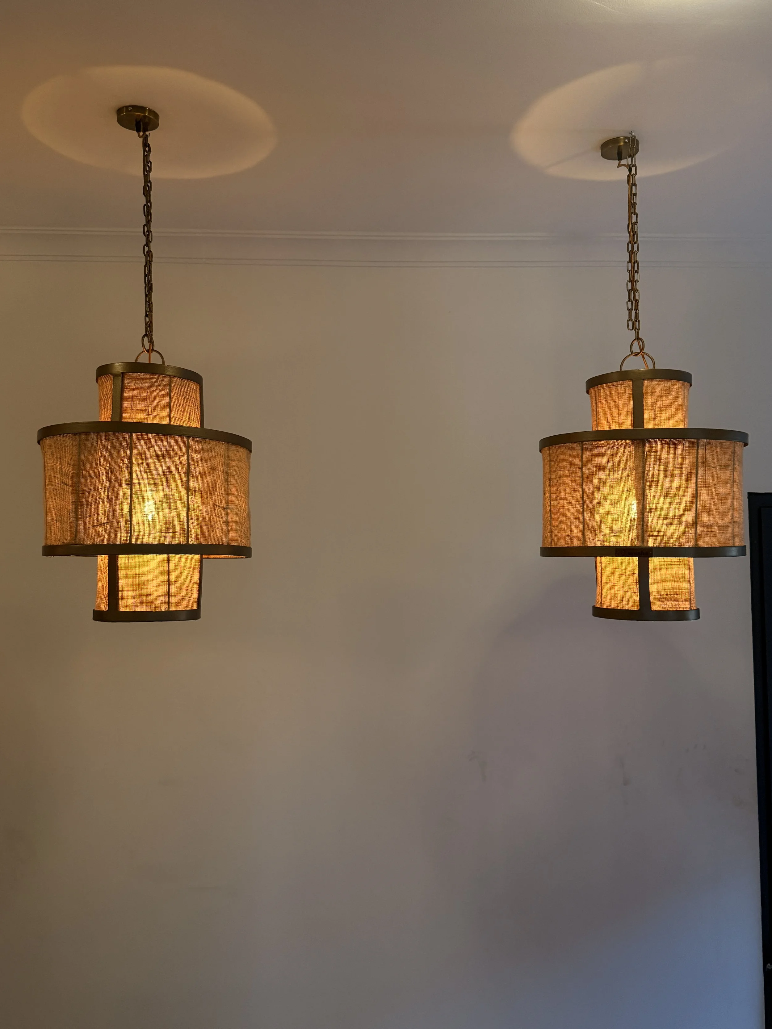 Two hanging pendant lights with warm orange glow, attached to a white ceiling with chains.