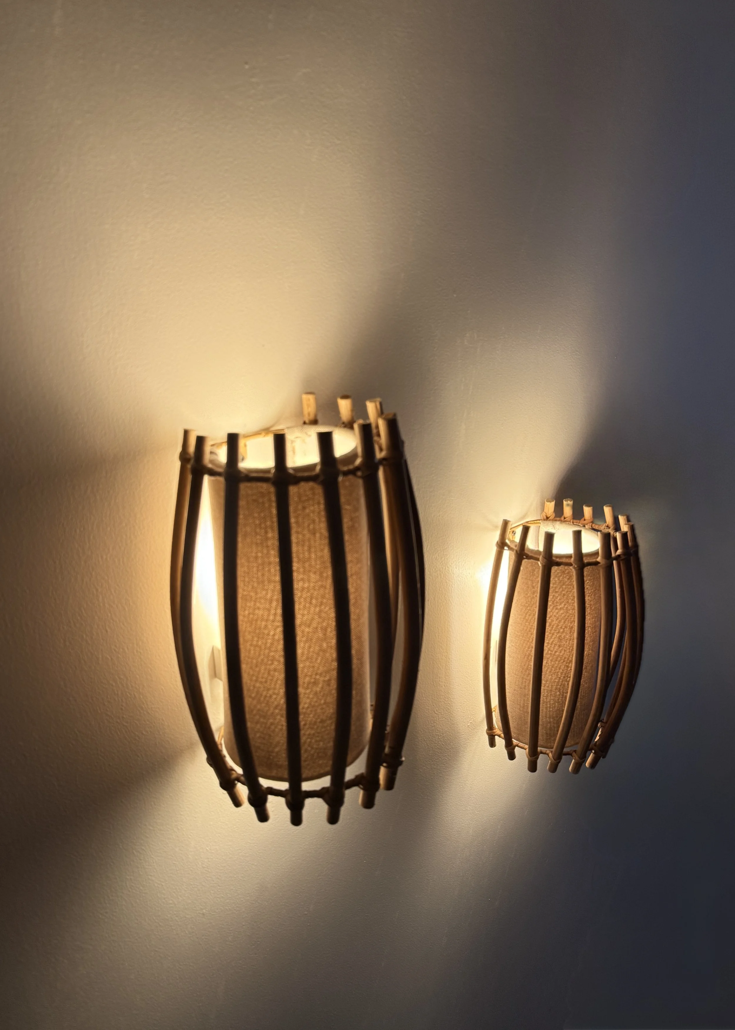A modern interpretation of woven lighting, designed with vertical wooden slats that diffuse light gently across the wall.