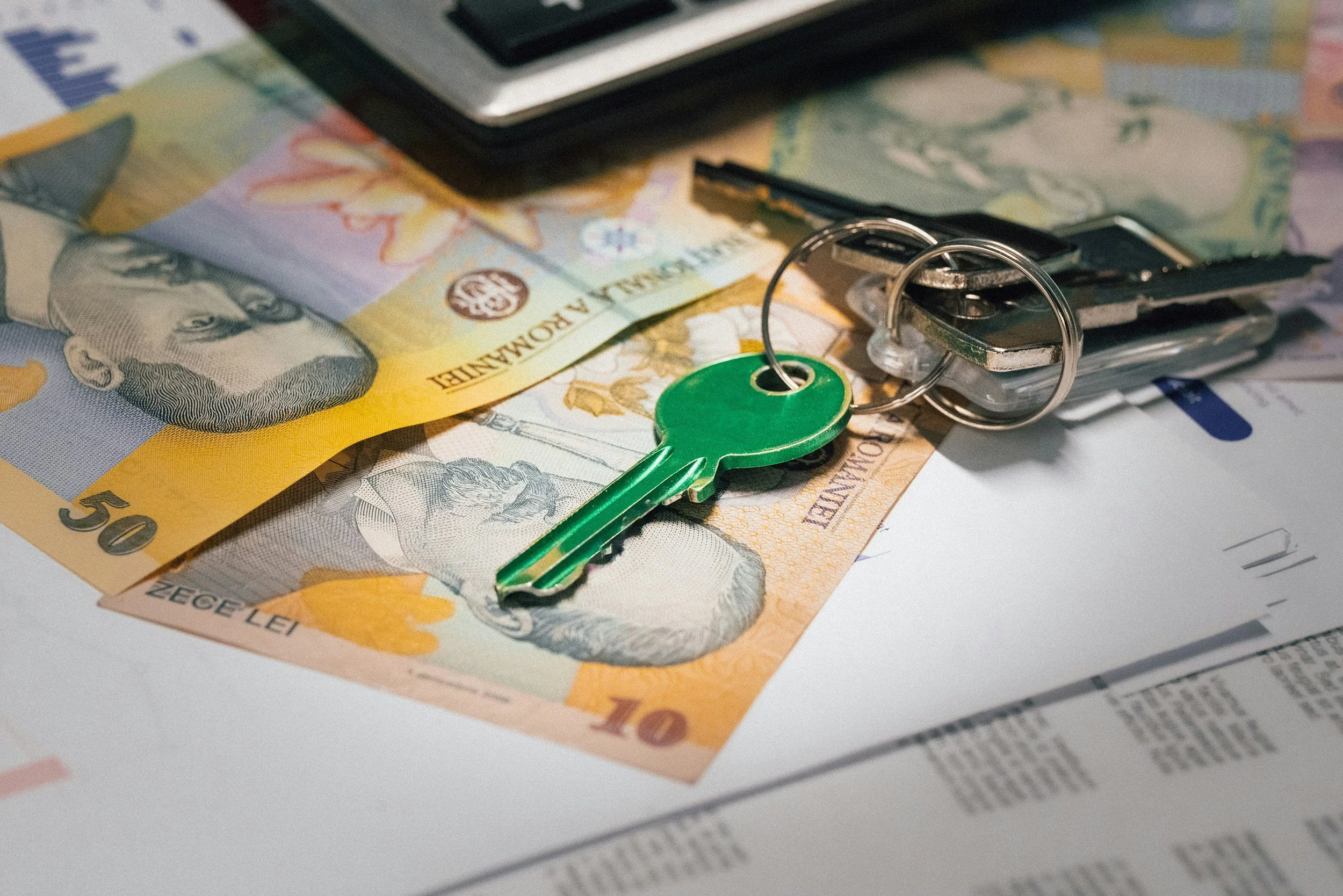 Canadian currency, a green key on a keyring, and a car key on a document.