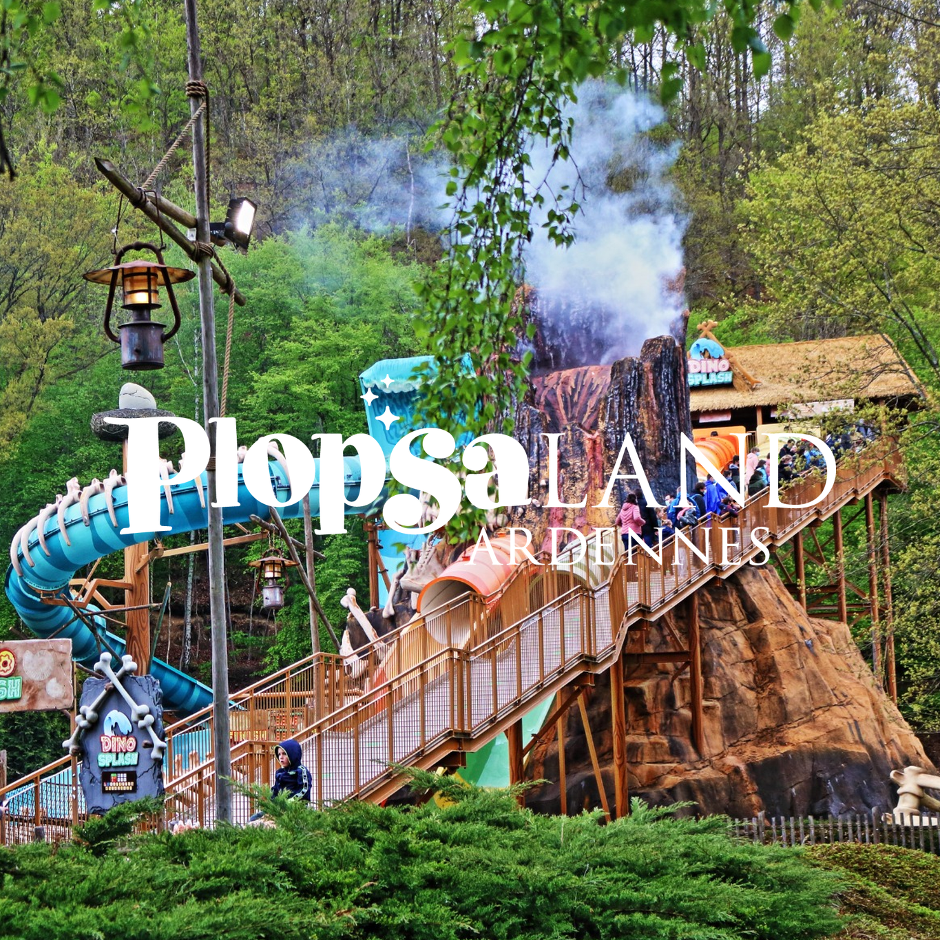 Blick auf die Abenteuerwelt im Freizeitpark Plopsaland Ardennes mit Wasserpark-Attraktionen, Wasserbahn und vielen Besuchern in der Natur.