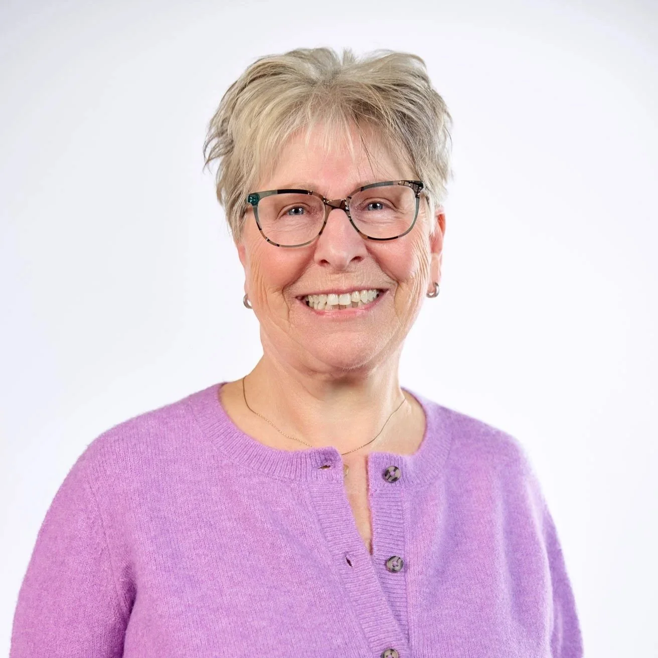 A smiling woman holding small colorful dumbbells in both hands.