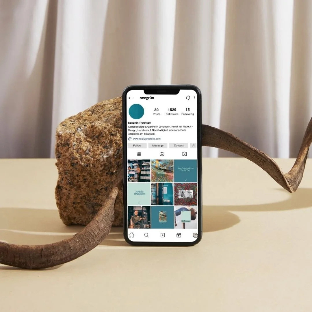 Die Instagram Seite vom Concept Store Seegrün auf einem Handy mit schönem Hintergrund, inszeniert vom Studio für Digitales CHCHCH.