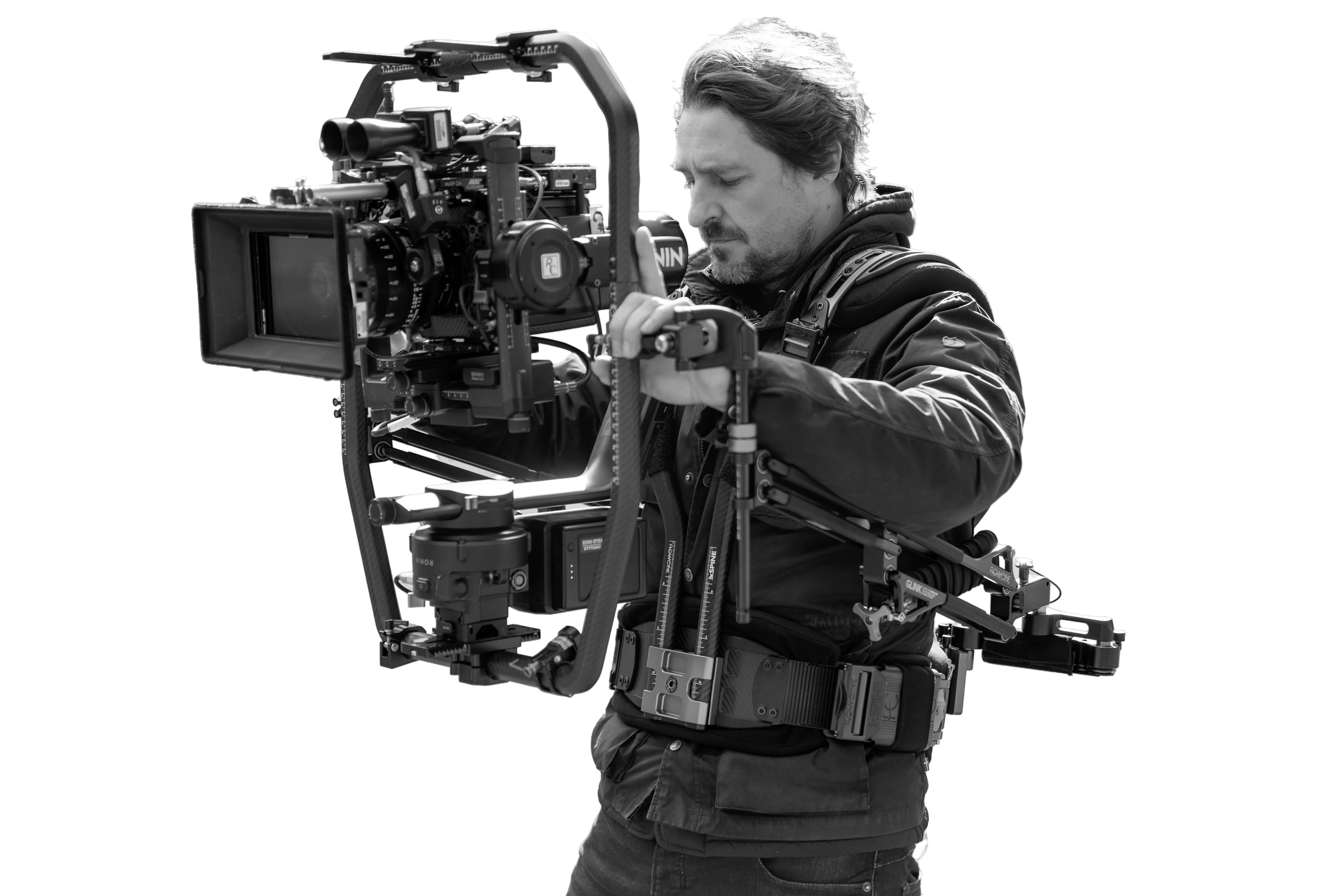 A man operating a professional film camera using a Ronin 2 and Glink system on a film set.