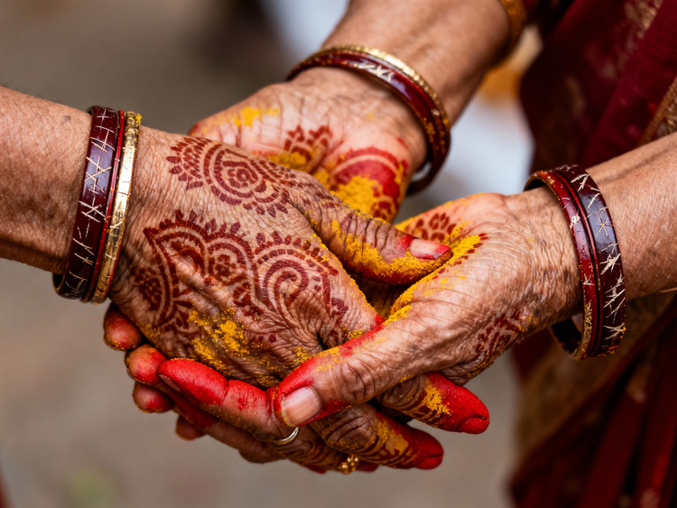 Mains ornées de mehndi et de poudre jaune et rouge