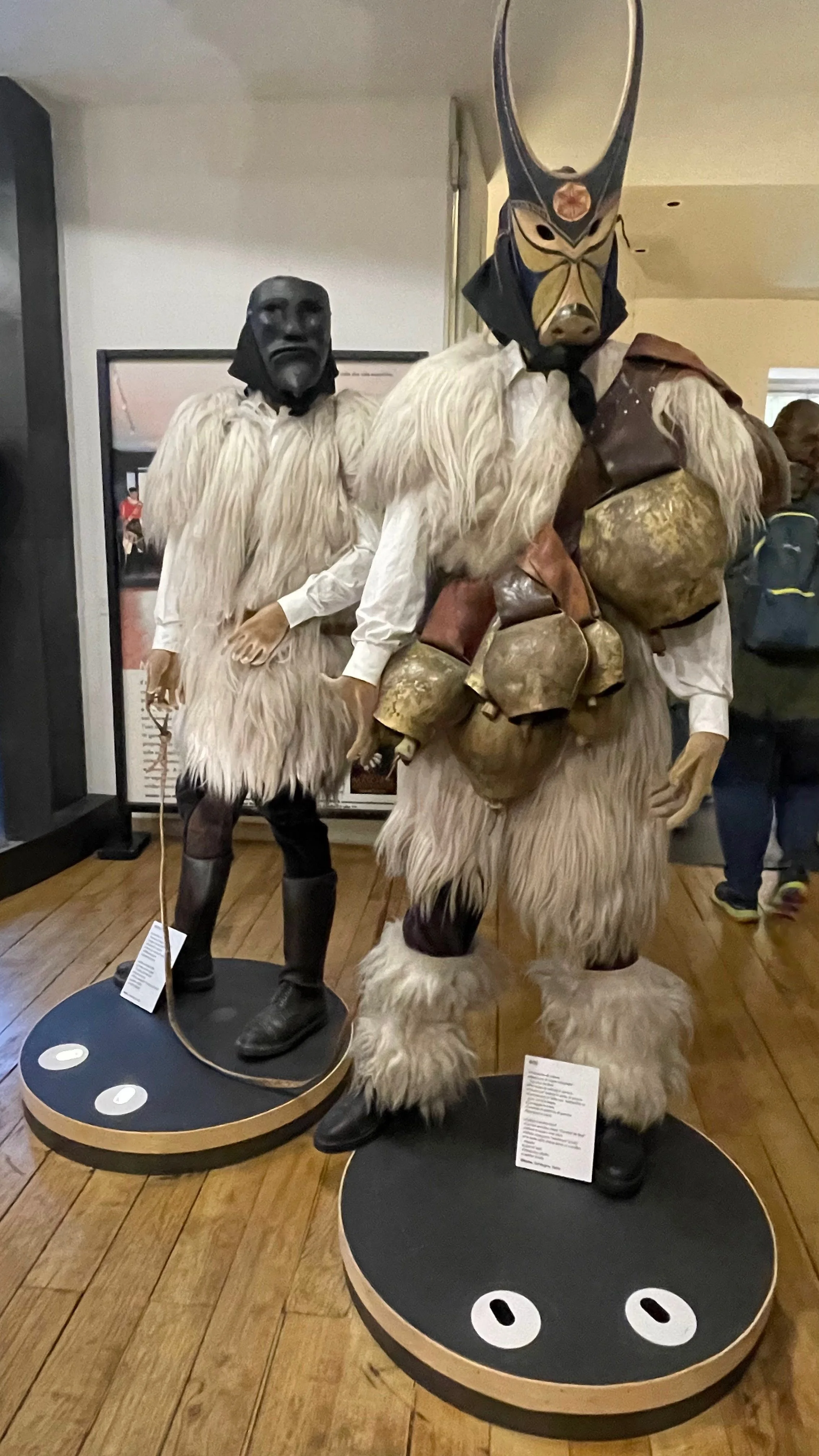 Two figures dressed in traditional Yeti costumes with masks, standing on display platforms in a museum or exhibit.