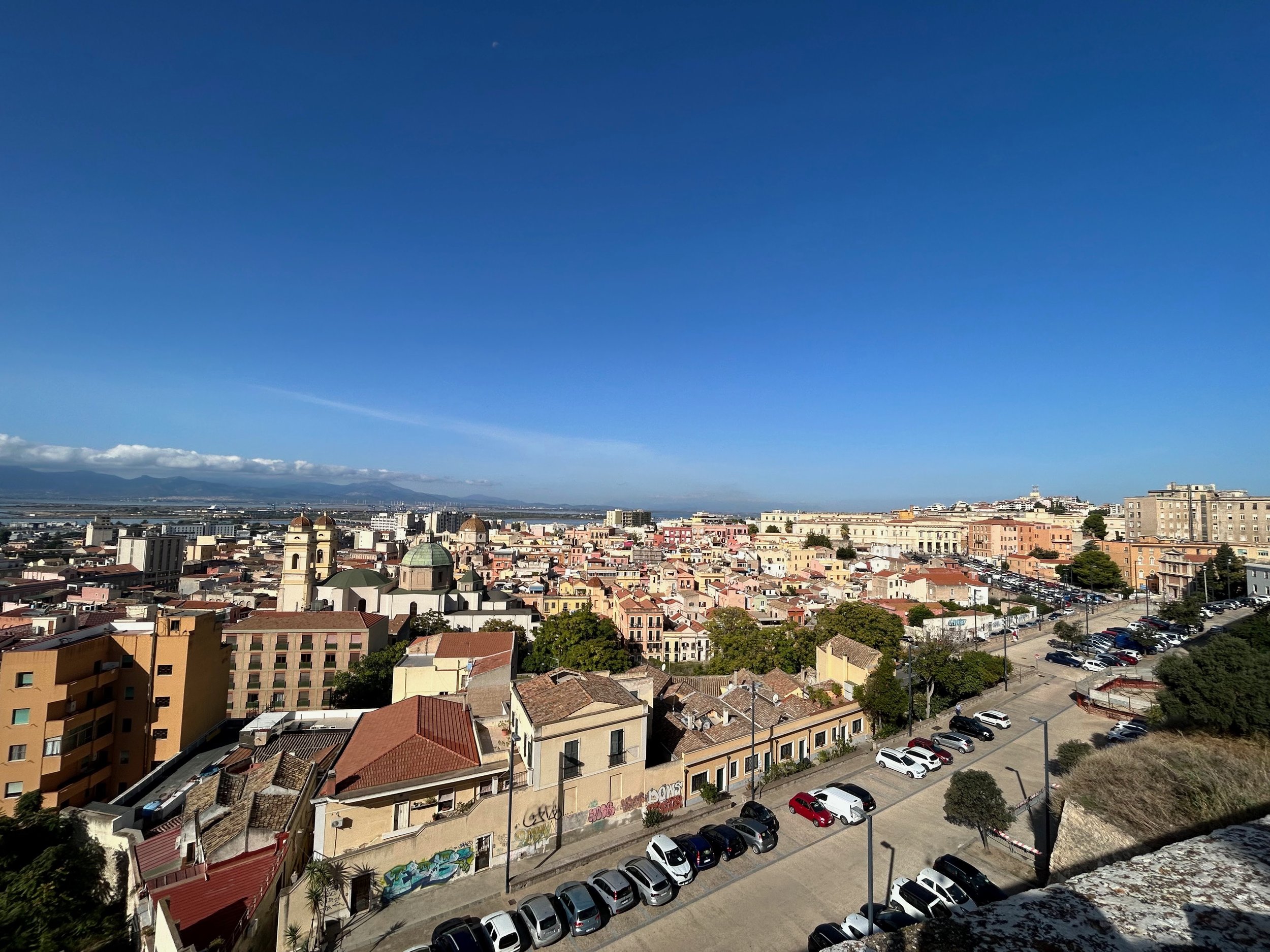 Cityscape view of a downtown area with buildings, churches, parking lots, and a clear blue sky.