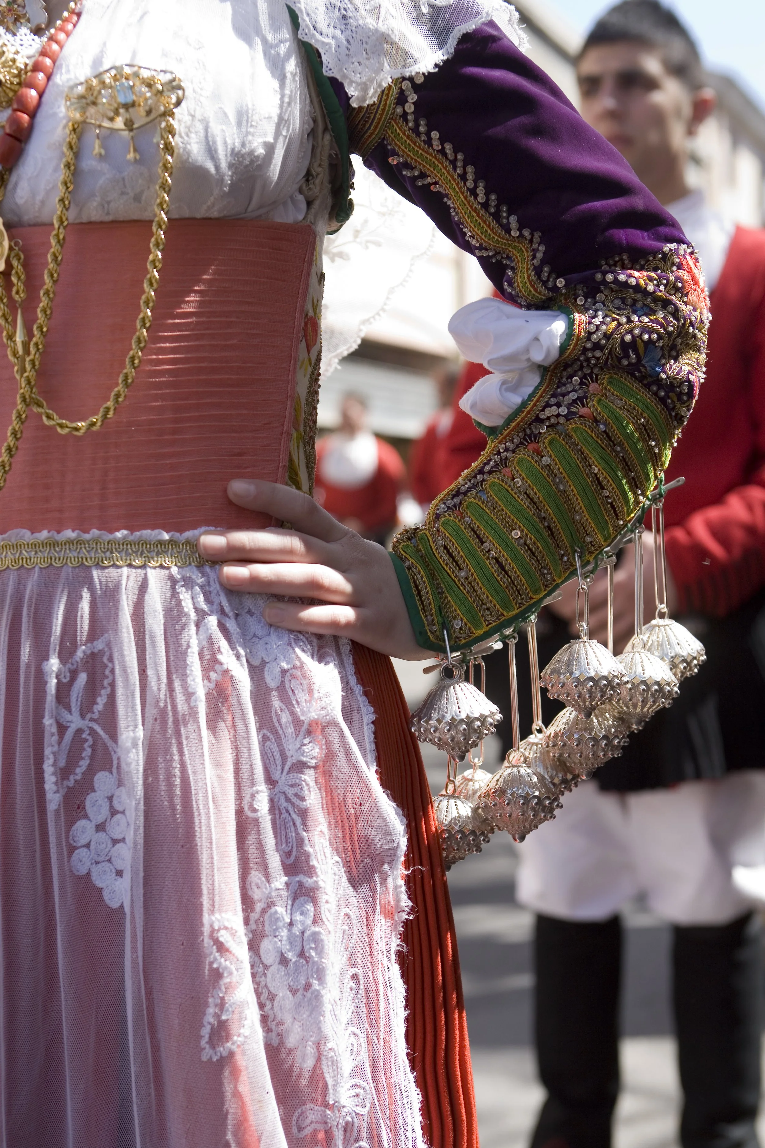Woman dressed in traditional Sardinian folk costume with intricate embroidery, lace, and jewelry, participating in a cultural event or parade.
