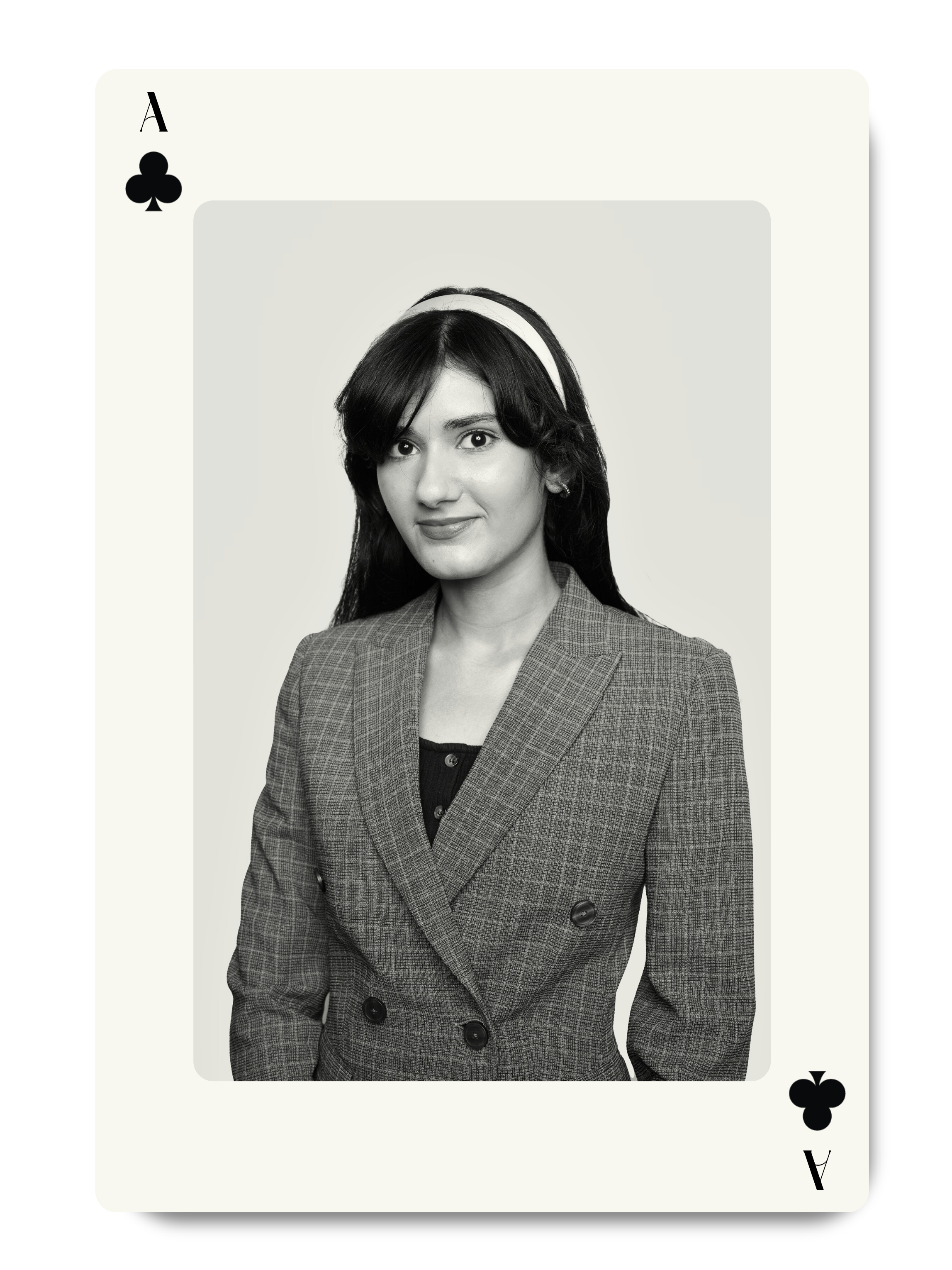 Black and white photo of a woman in a plaid blazer, with long dark hair, smiling softly, wearing a headband, framed within a playing card design.