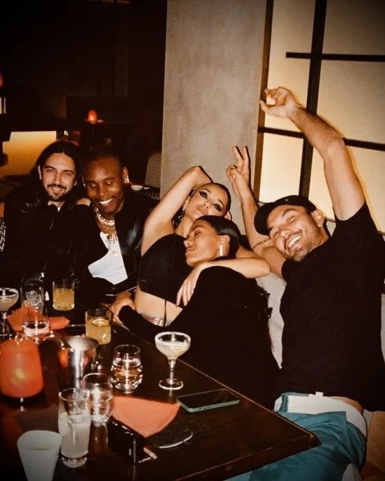 Group of five friends celebrating at a dinner table with drinks, smiling, and having a good time.