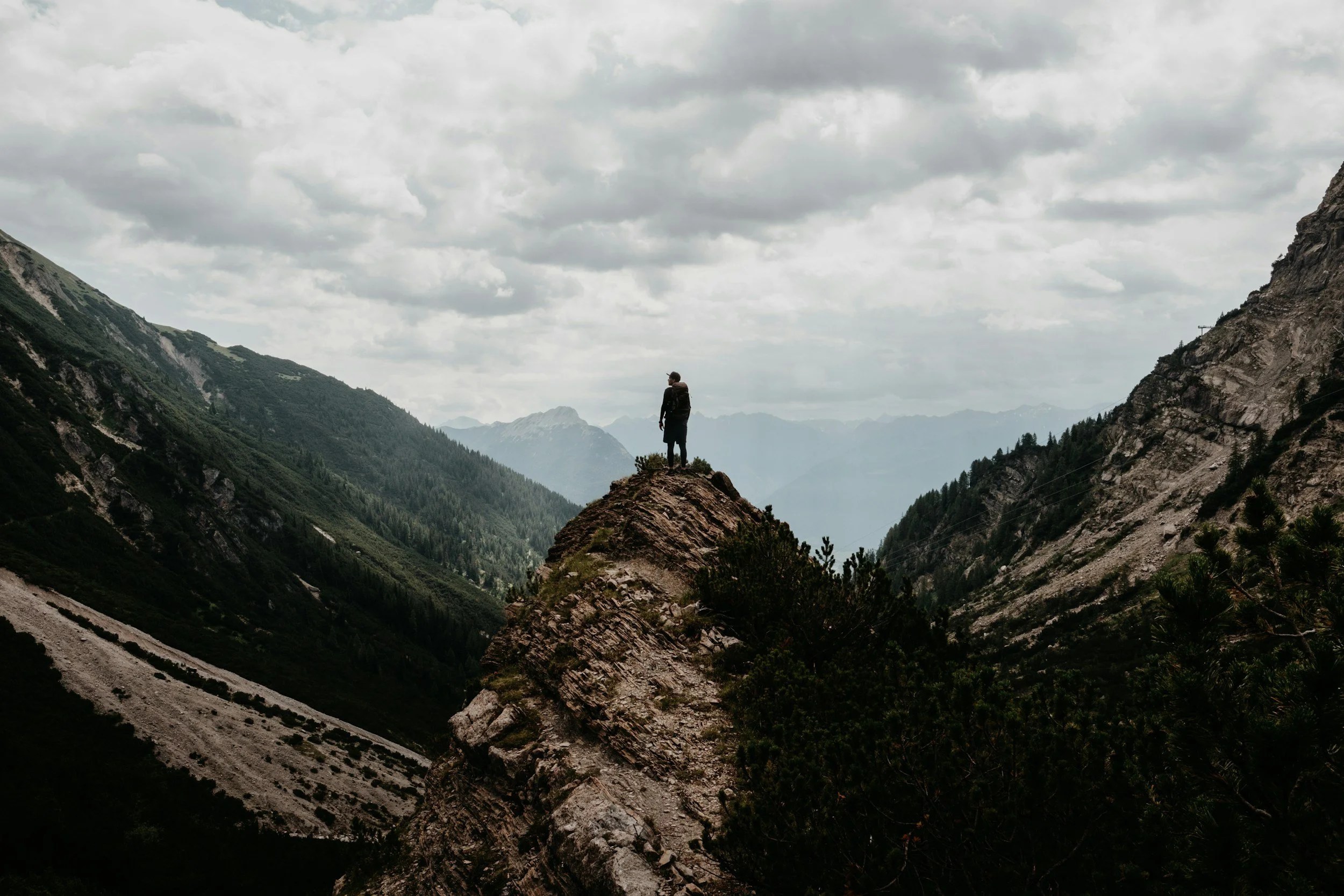 A person stood on a mountain looking out over a mountain range