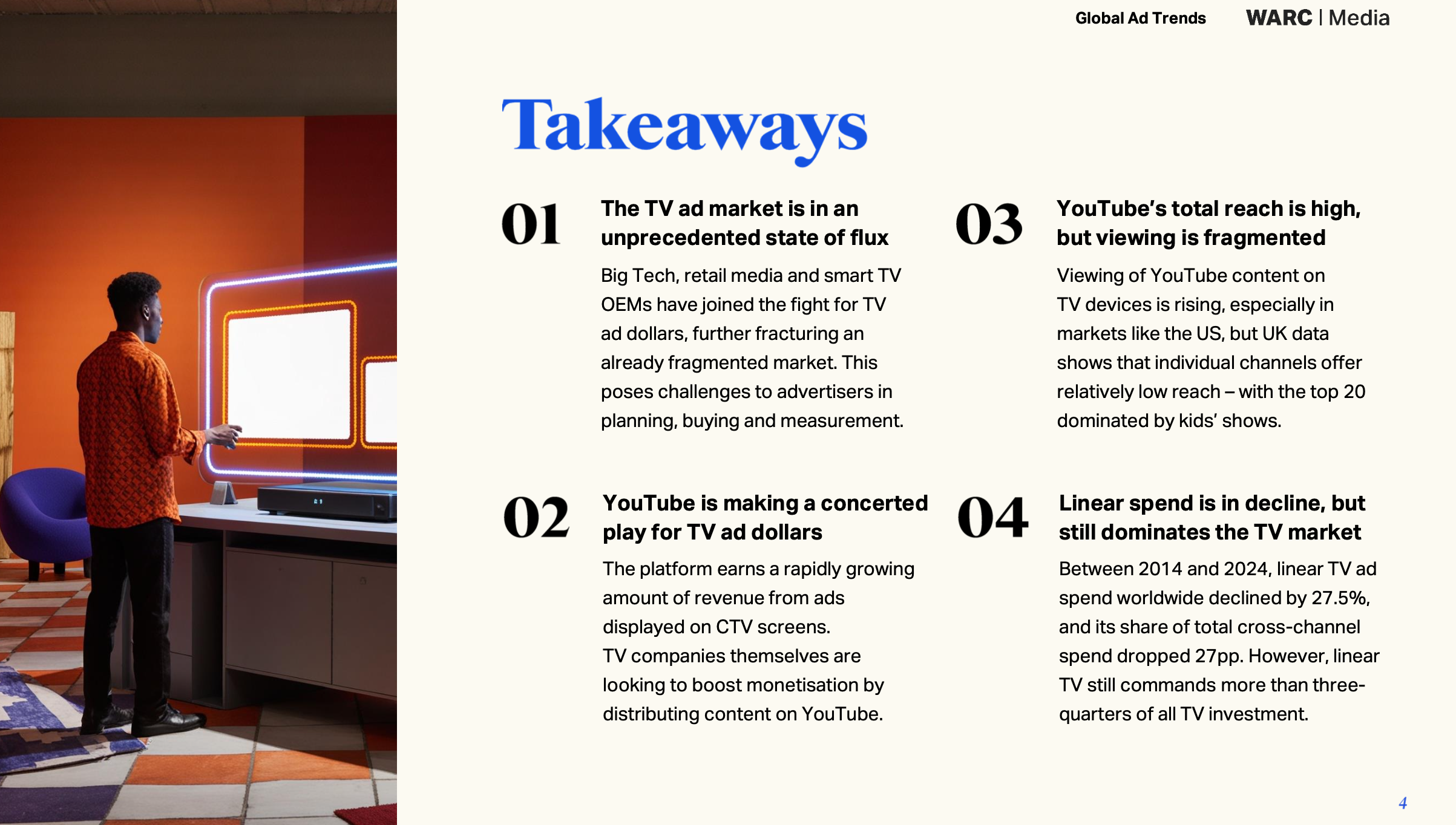 A person standing near a modern TV screen in a room with orange and red walls. The person is dressed in an orange patterned jacket and black pants, looking at the TV, which has a neon outline.