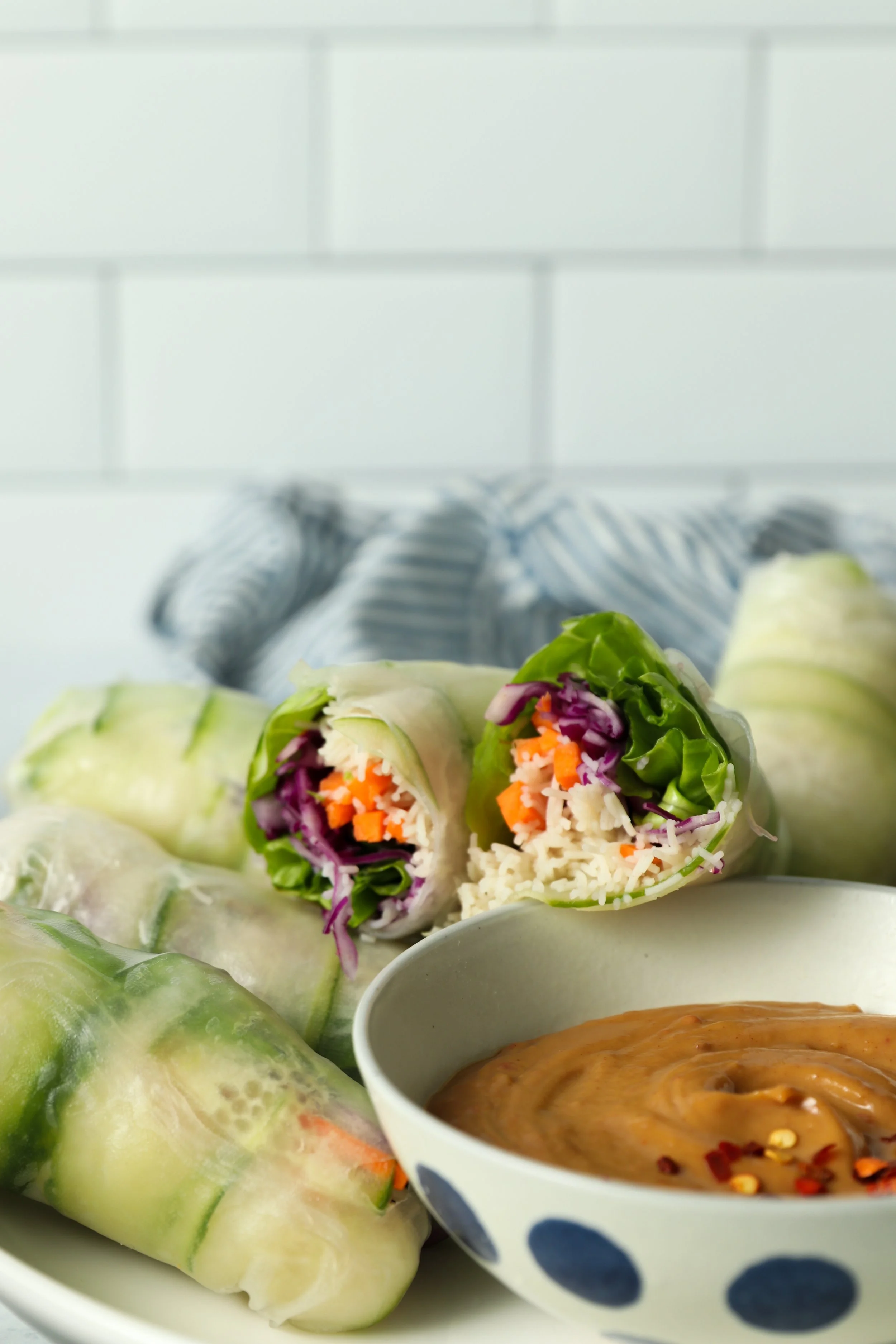 Fresh vegetable spring rolls with peanut dipping sauce on a white plate.