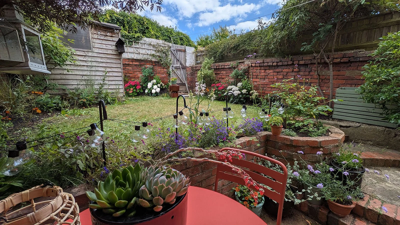 Beautiful cottage garden with roses, hydrangeas and pots with succulents