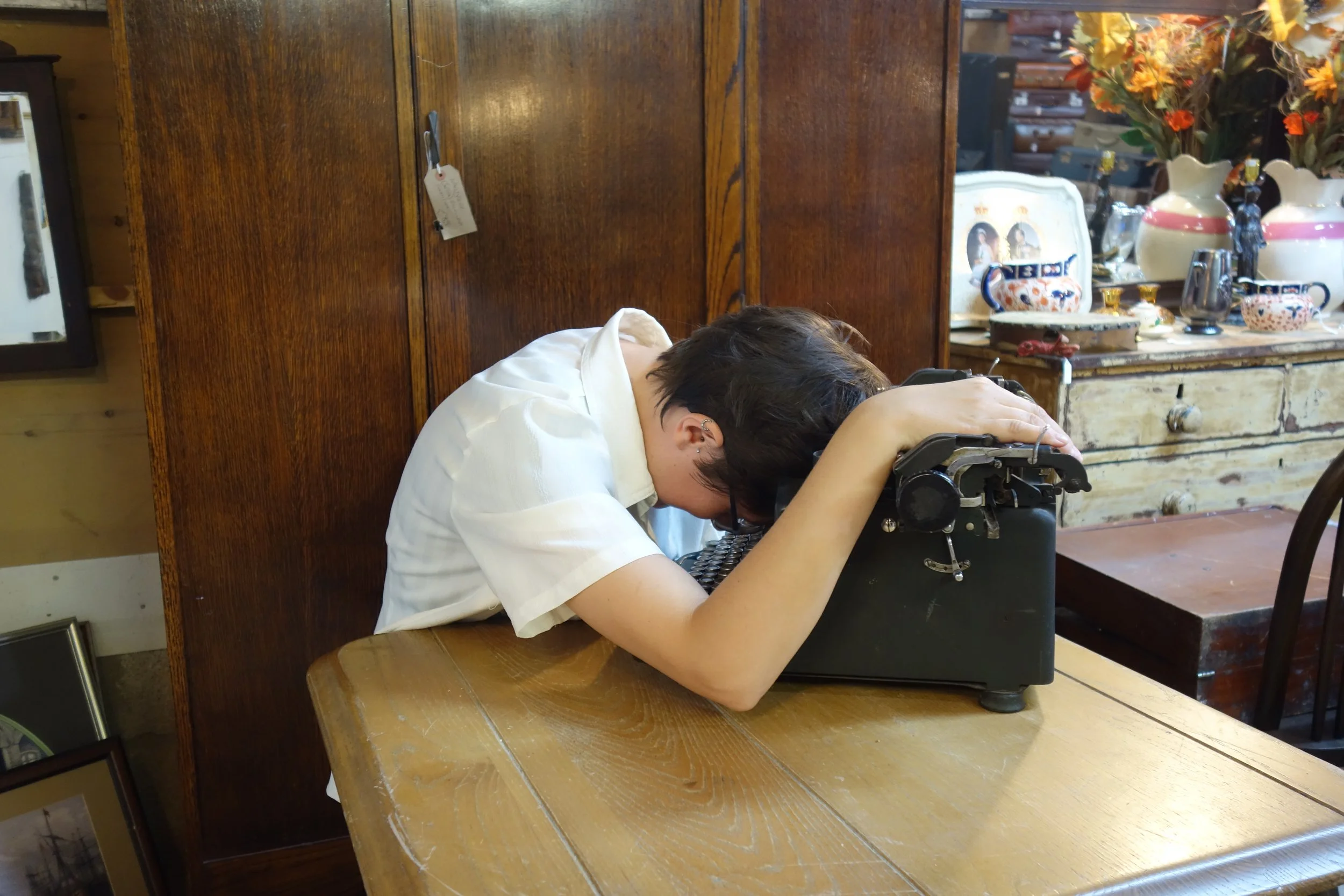 A woman sprawls despairingly over an old typewriter