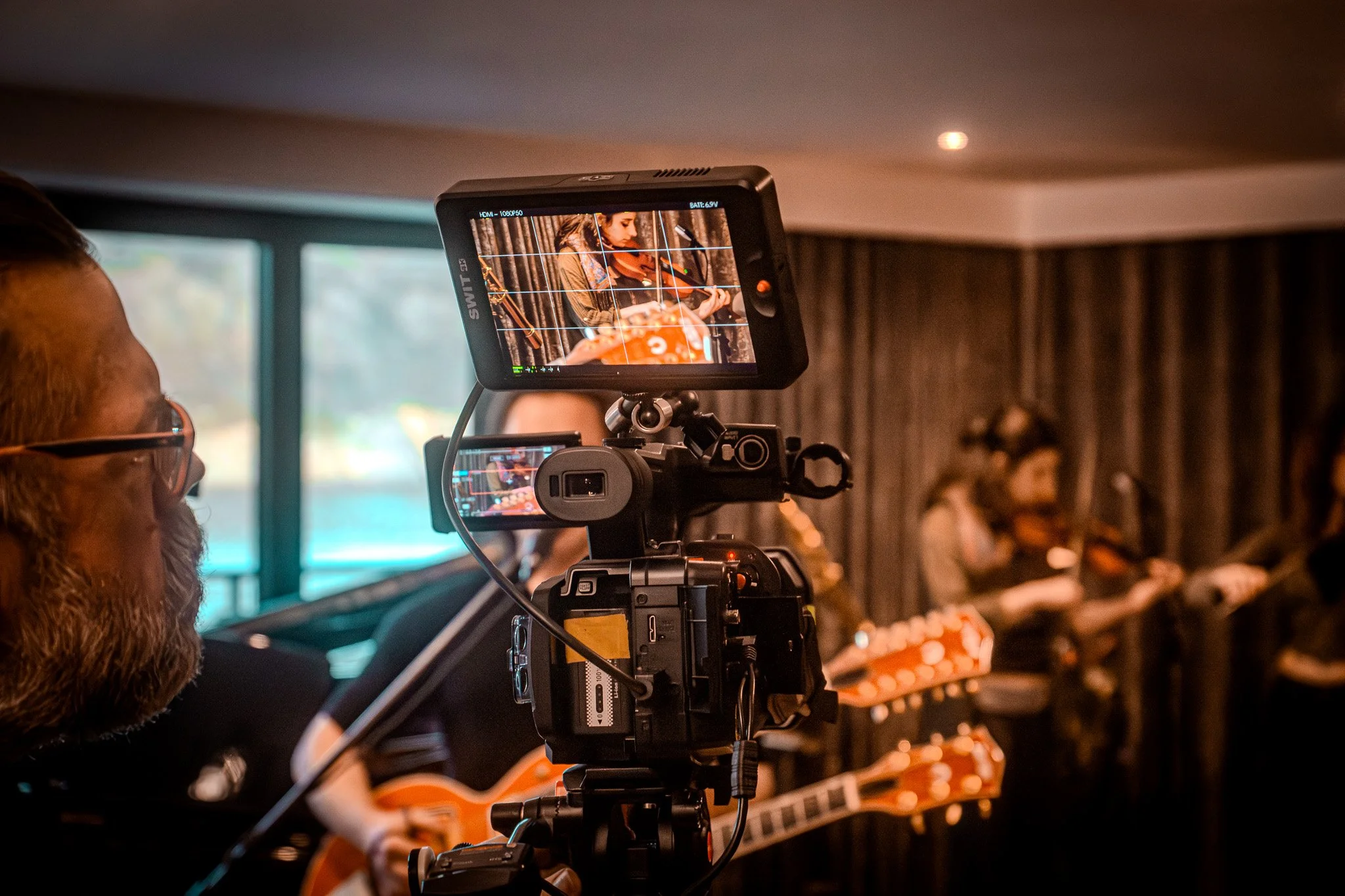 A professional video camera capturing a musician playing a violin at a live performance.