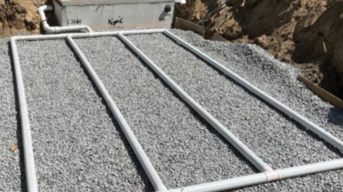 Construction site with gravel and PVC pipes for plumbing or drainage.