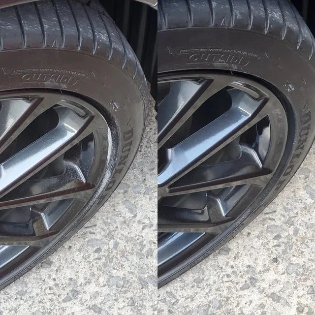 Close-up of two car wheels with alloy rims on rough pavement, showing before and after cleaning or polishing.