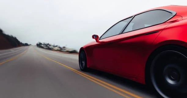 Red car driving on an open road in overcast weather