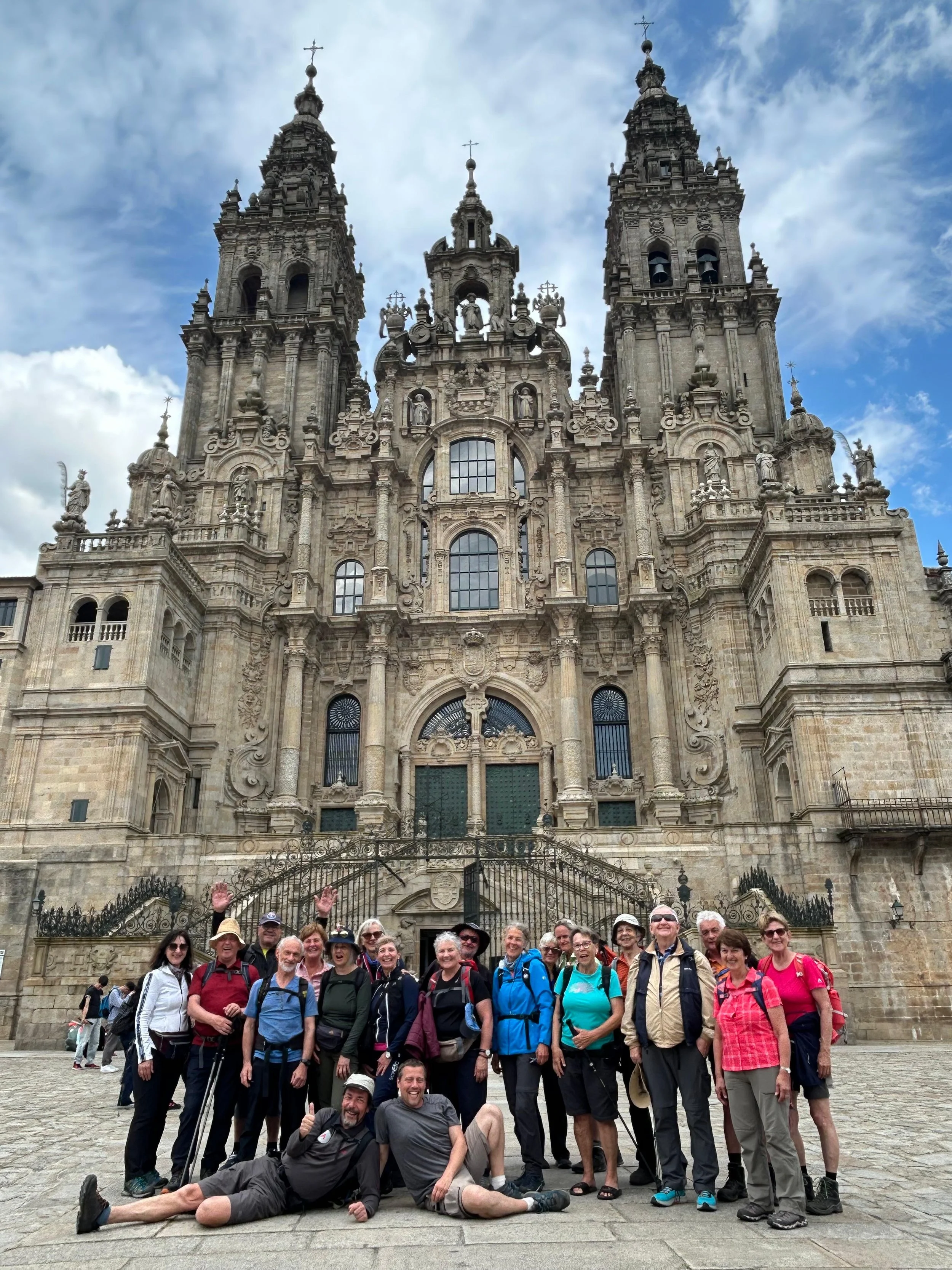 Eine Gruppe von Touristen poseiert vor einer großen barocken Kathedrale in Spanien, wahrscheinlich die Kathedrale von Santiago de Compostela.