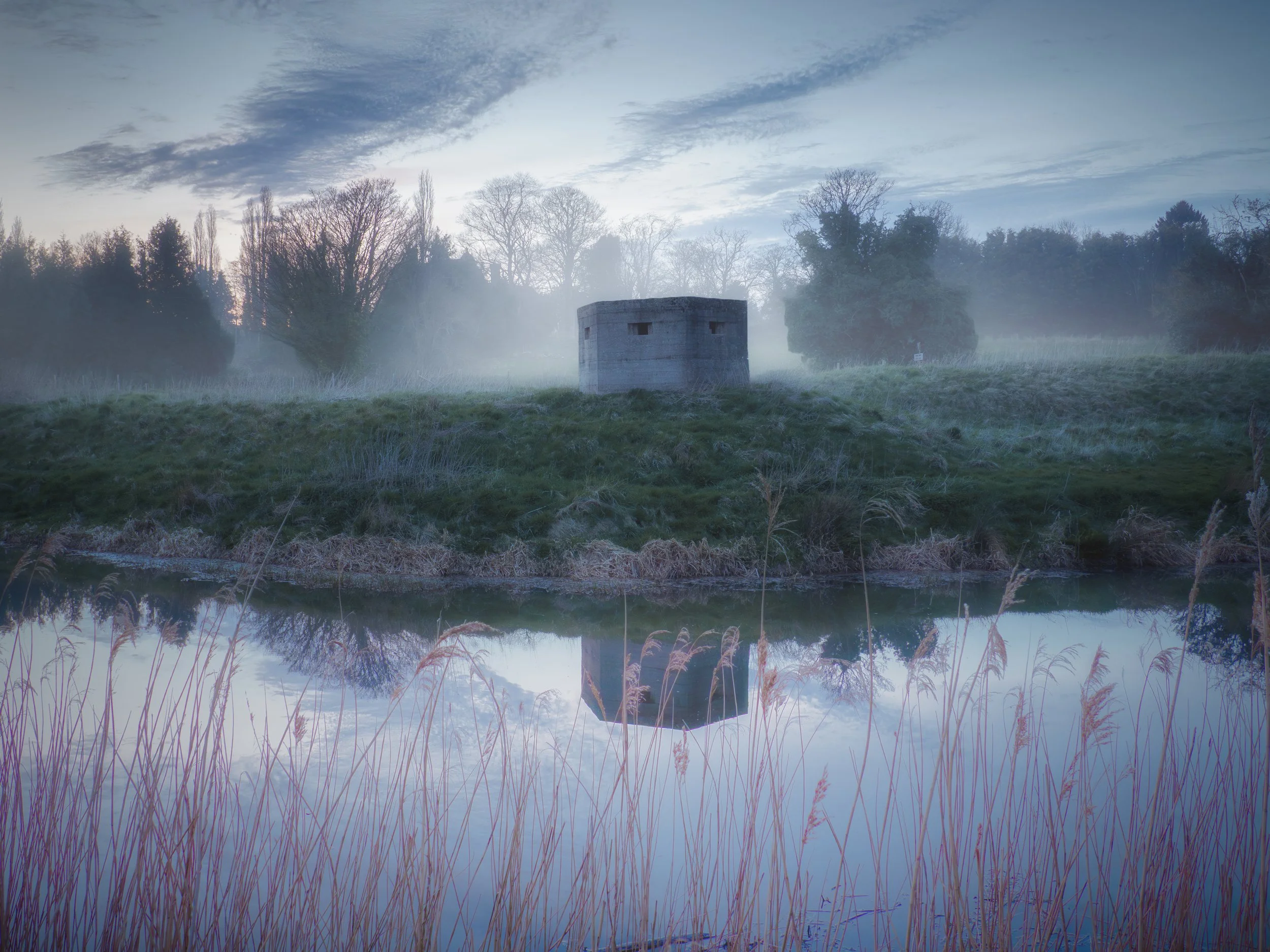 Misty Landscape with Concrete Bunker Reflected in Water at Dawn.jpg