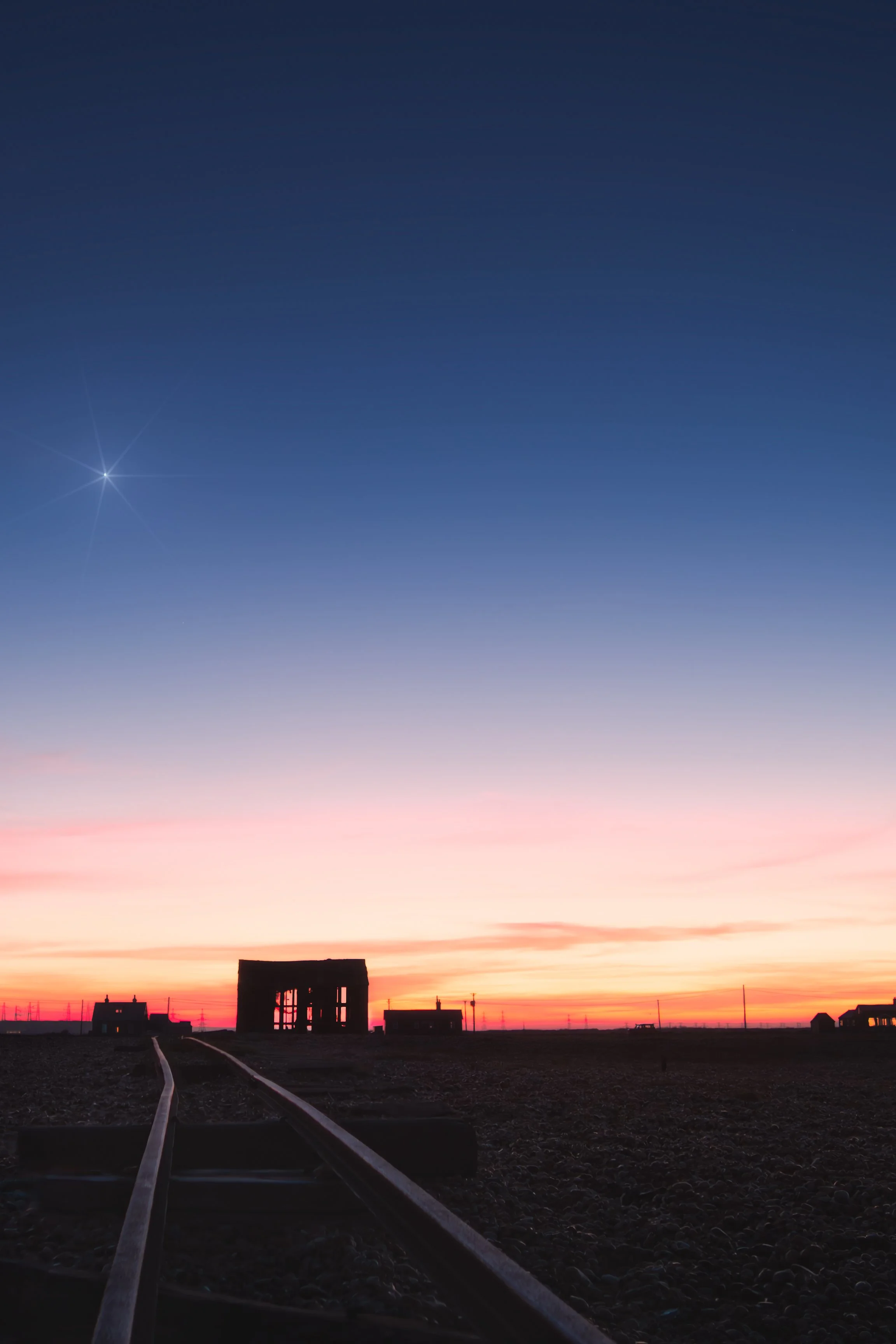 Railway Tracks Leading to Abandoned Structure at Sunset.jpg