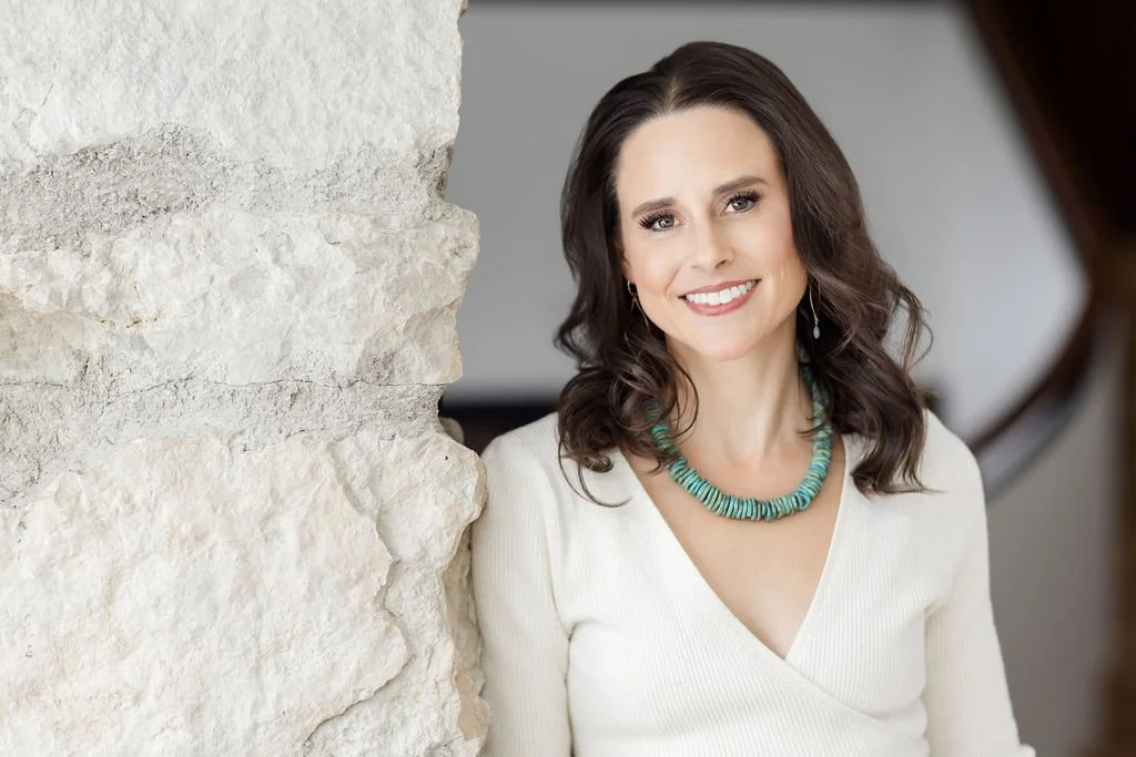 fertility-coach-dressed-in-white-leaning-against-stone-wall