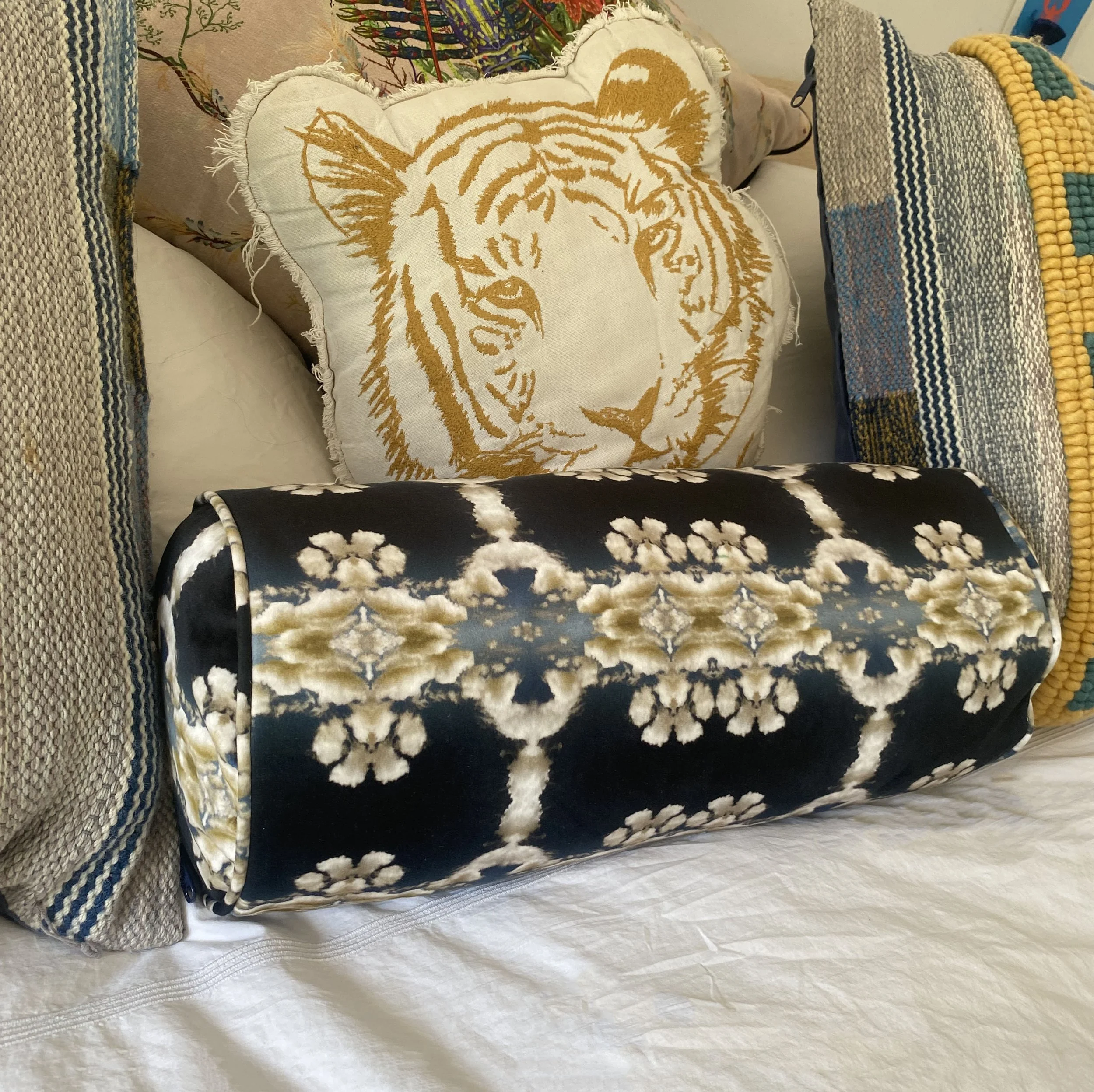 Decorative pillows on a bed, including one with a tiger's face and another with a black and white floral pattern.