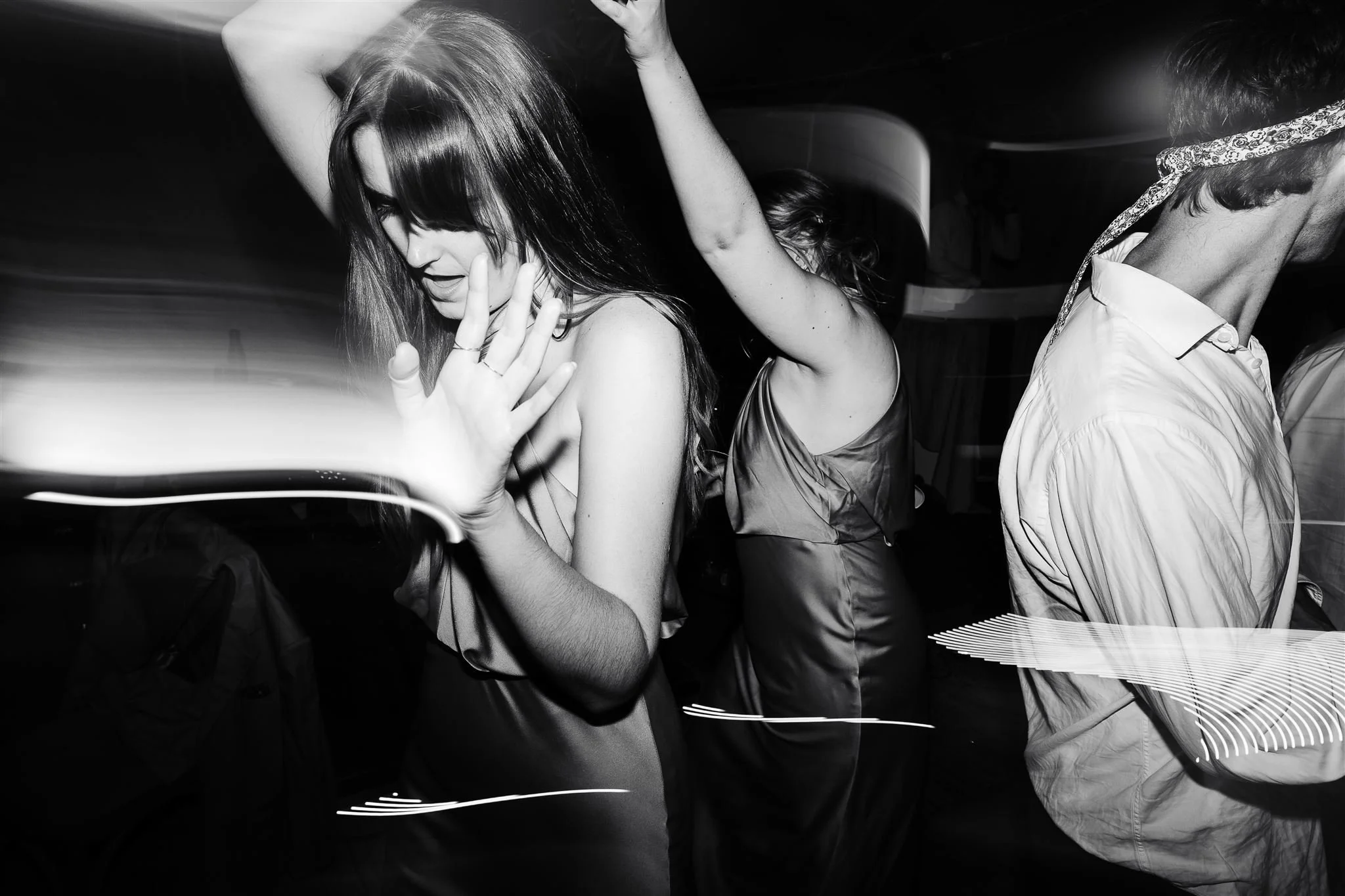 People dancing at a party, black and white photo, woman with hands raised, other people in background