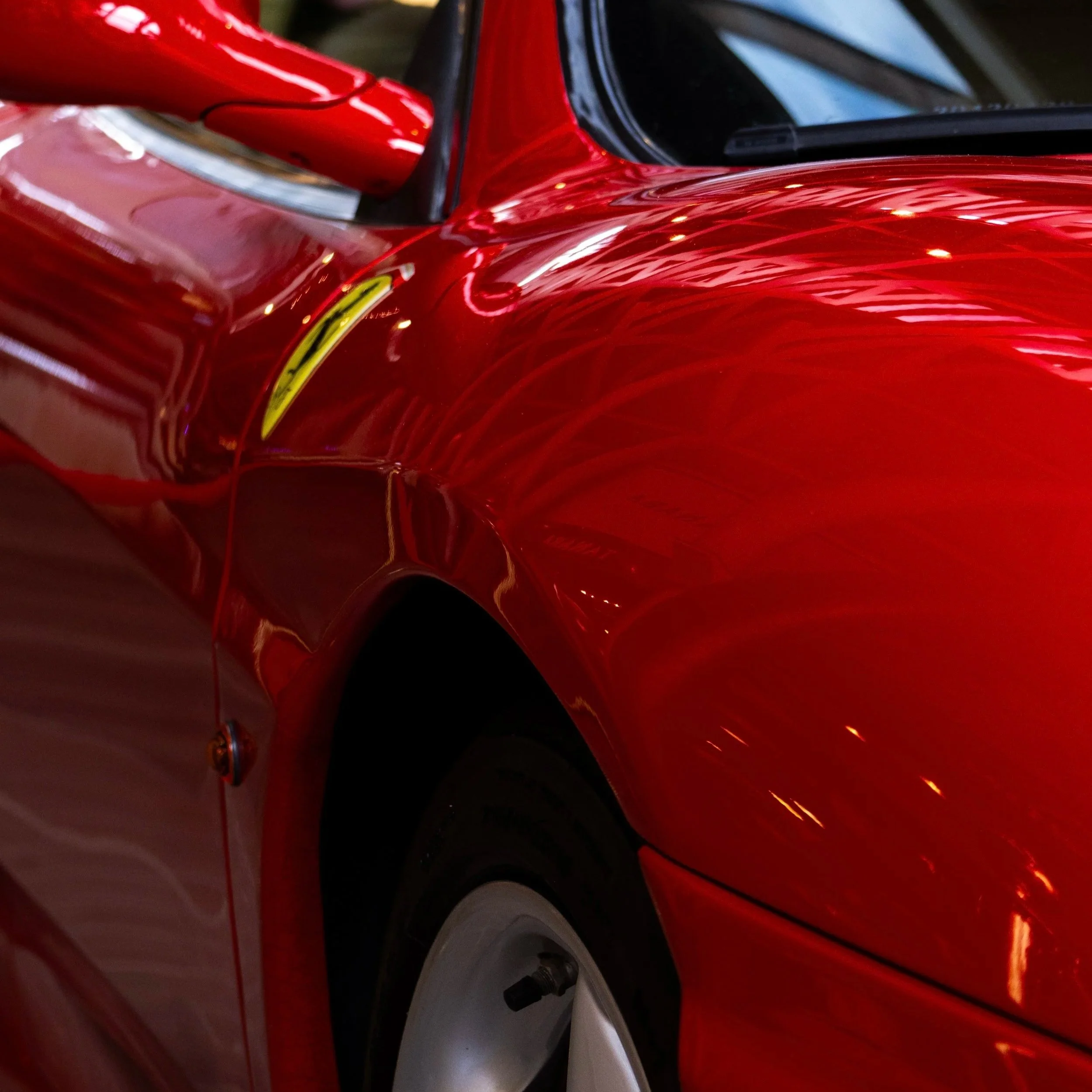 Foto close-up de uma carroceria vermelha de carro esportivo.