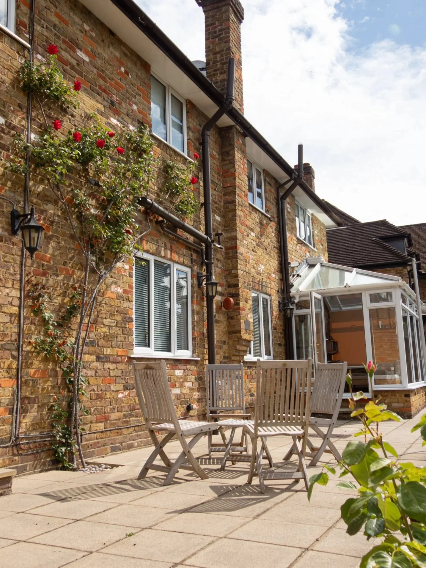 Garden patio of a conservatory with garden furniture & roses