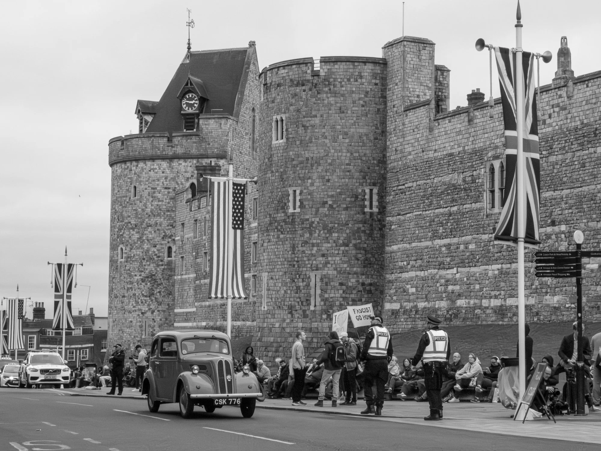 Protest in front of Windsor Castle with police, american flag, vintage car Ford Popular, pictured in Black & White