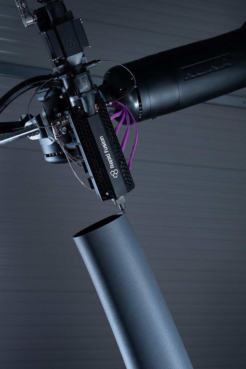 Close-up of a drone or robotic device with a cylindrical component and wiring, labeled 'Raytheon Raytheon Fusion'.