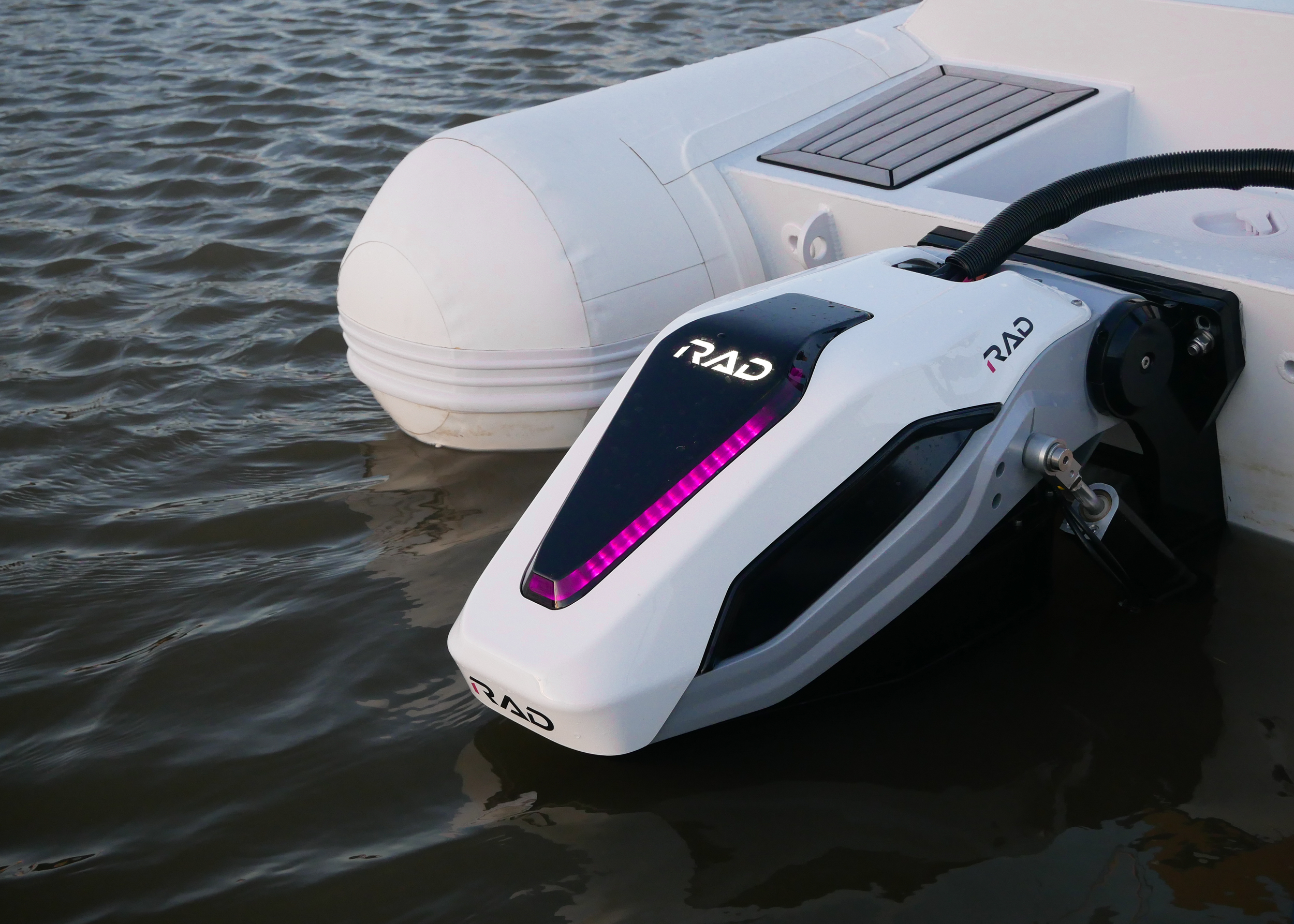 Close-up of a boat motor on water, showing the brand 'RAD' and a black vent, with water ripples around it.