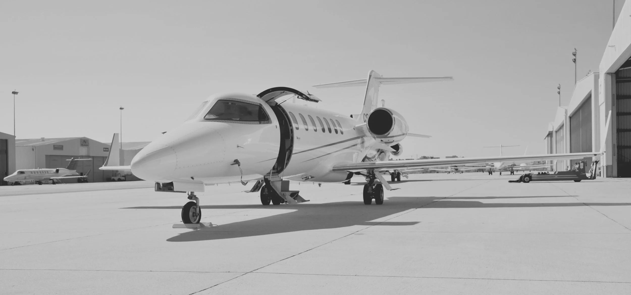 Private jet parked outside an aircraft hangar at an airport.