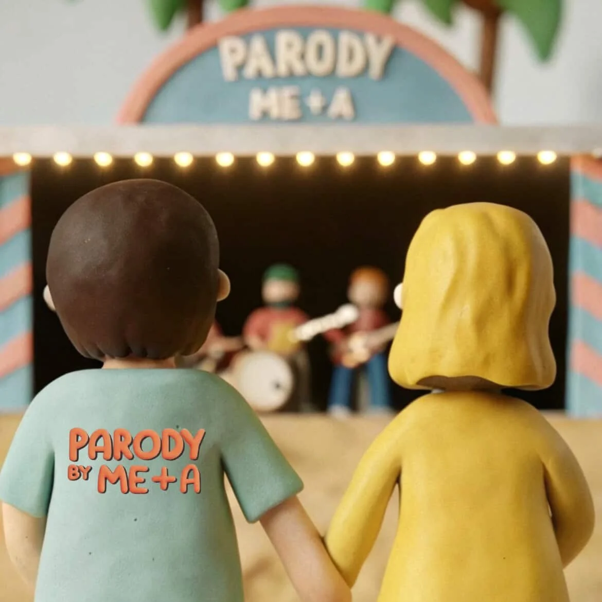 Two figurines holding hands watching a small band perform on stage with a sign reading 'Parody by Me + A' above the stage. song by JLynn theWriter.