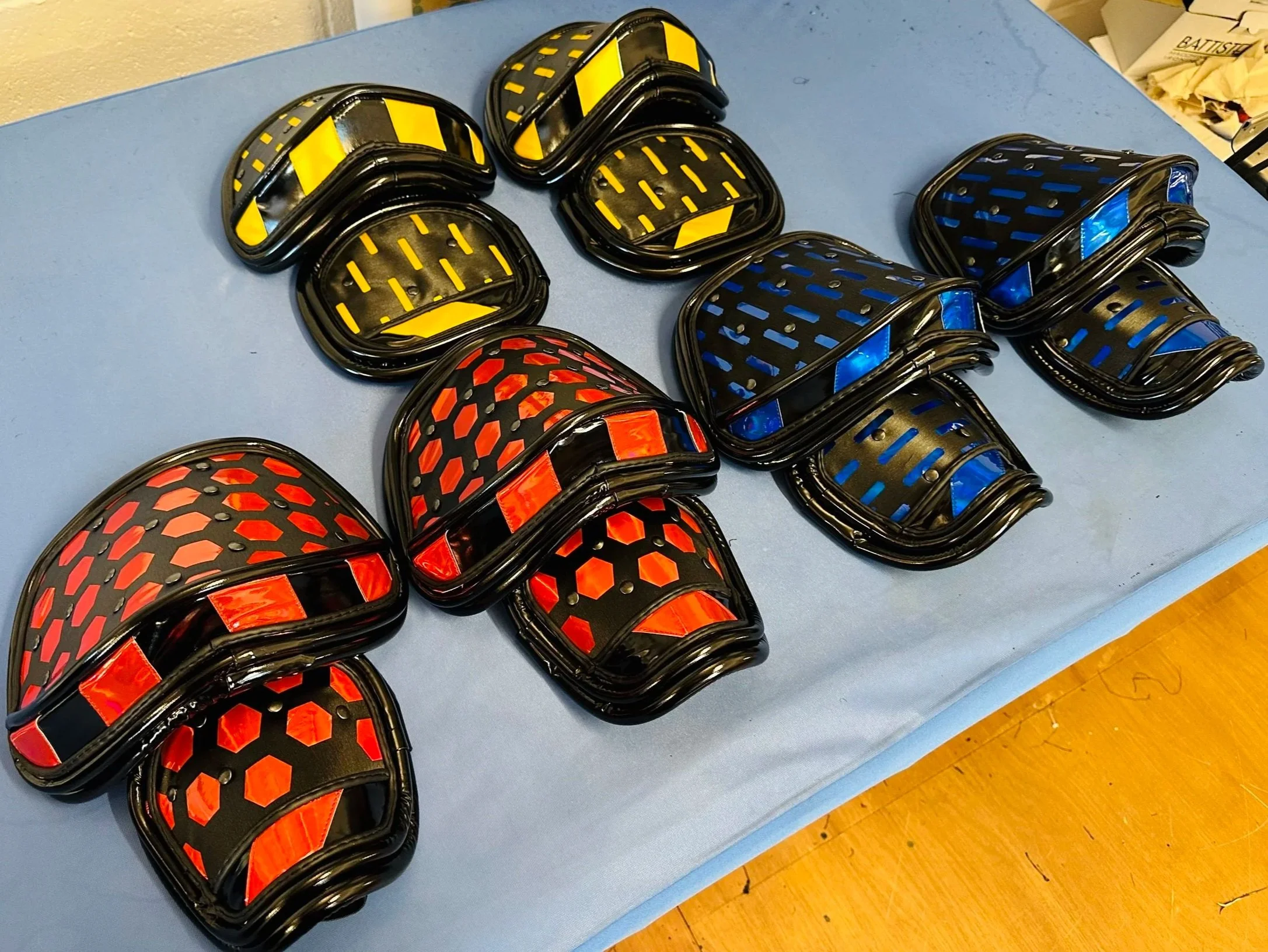Multiple sets of reflective ankle bands in yellow, blue, and red colors, arranged on a blue table.