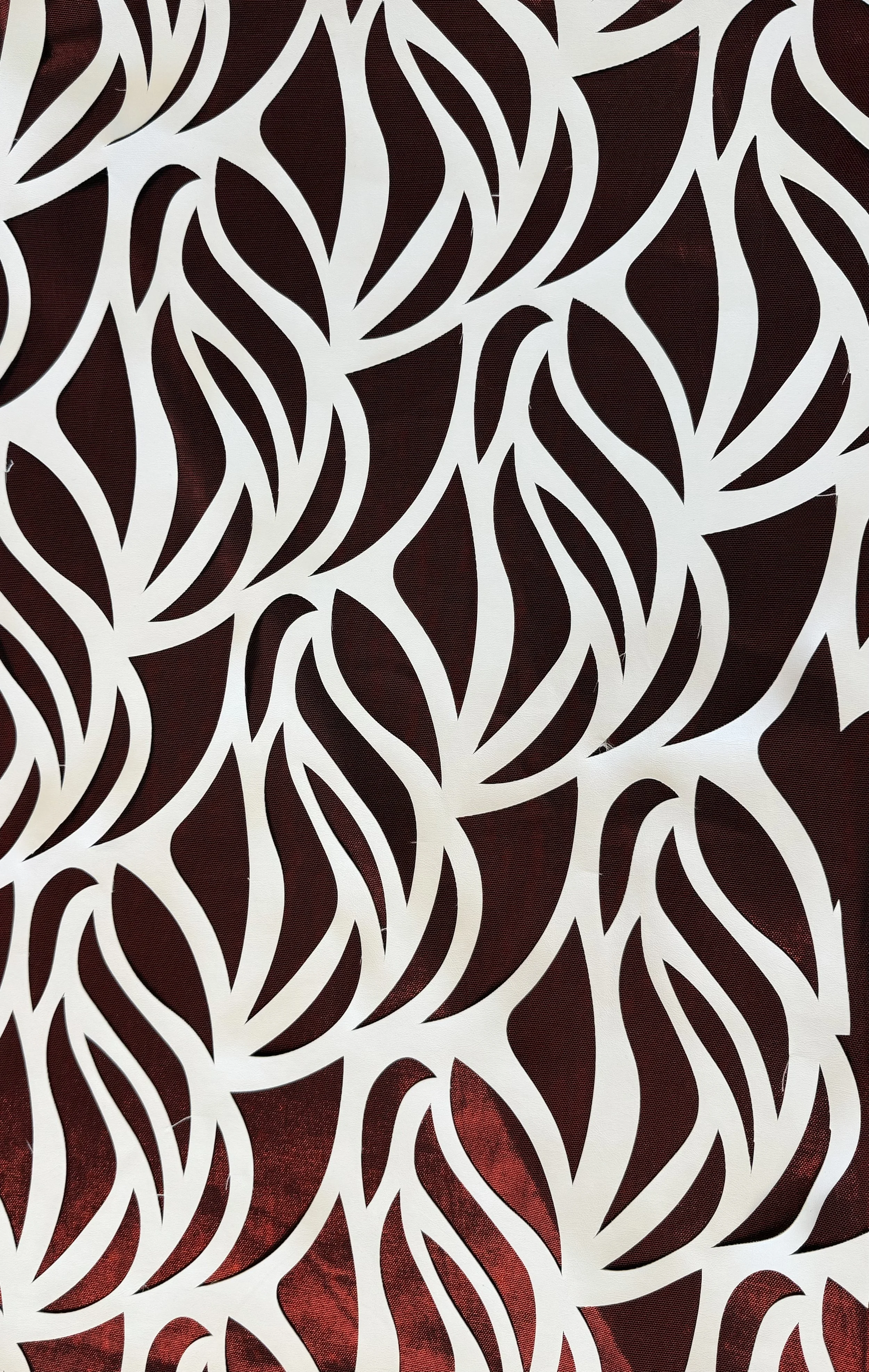 White decorative panel with an abstract leaf pattern, partially revealing a red background underneath.