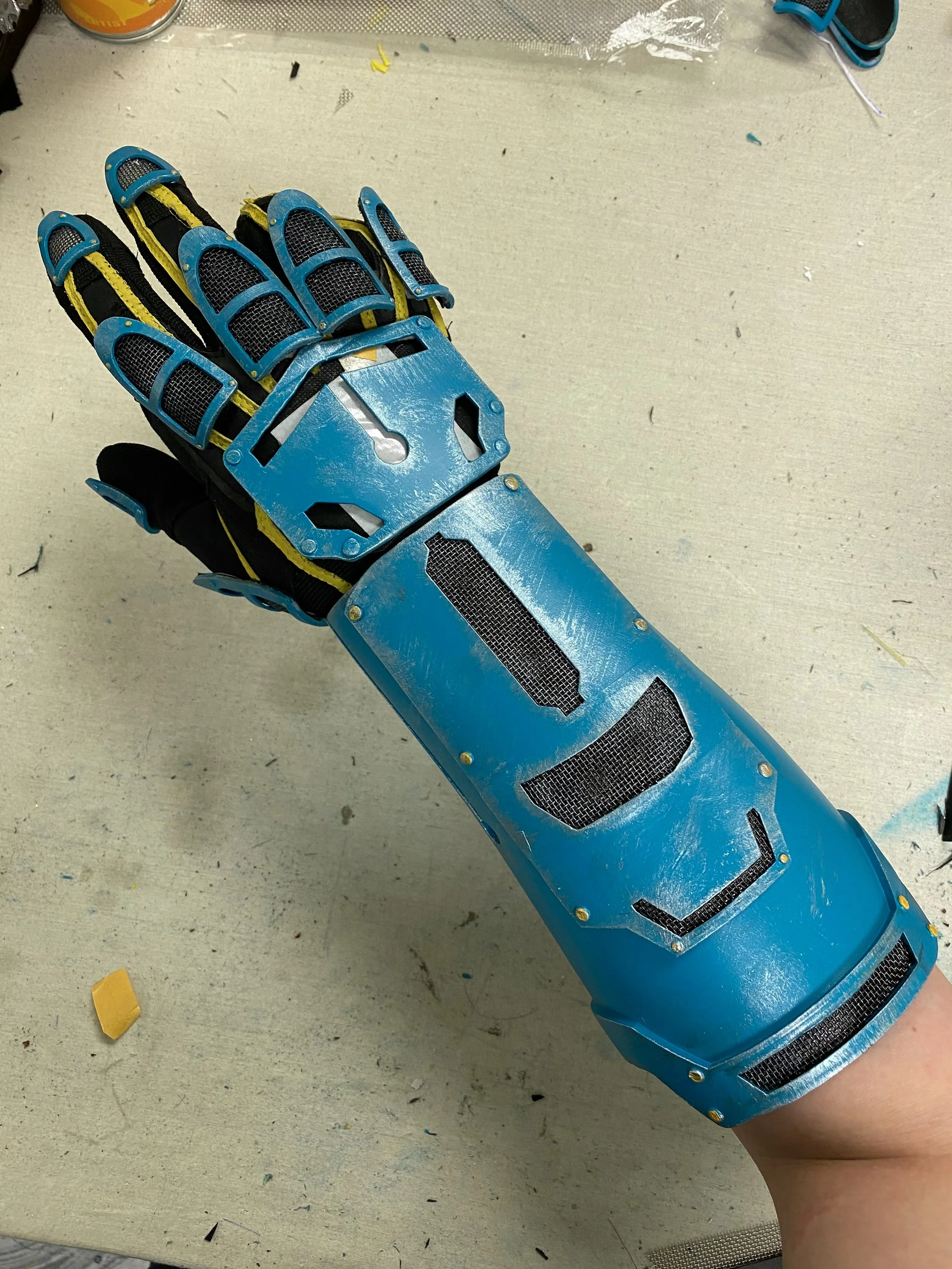A robotic prosthetic arm with a blue metal exterior and black mesh, designed to resemble a human arm. xbox, EE