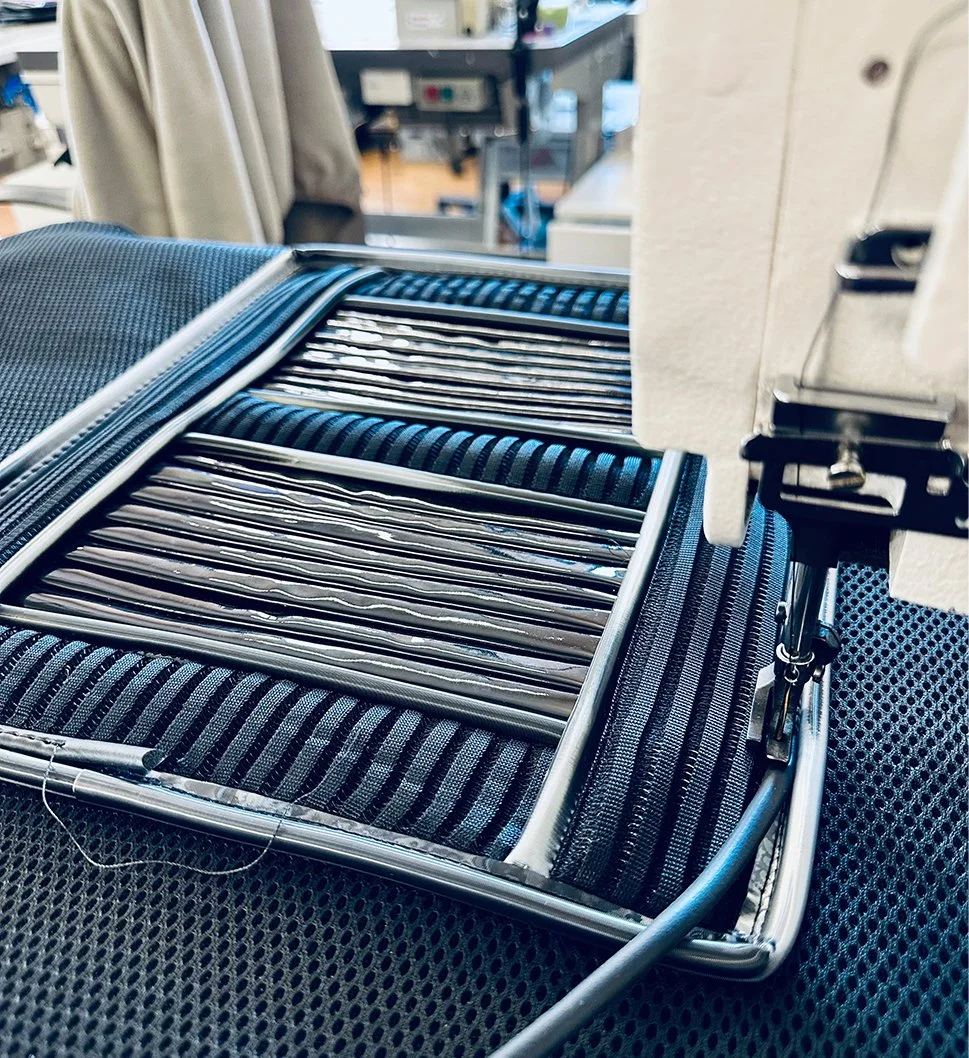 Custom costume making, multi-material technical fabrics and plastics being sewn under industrial sewing machine.