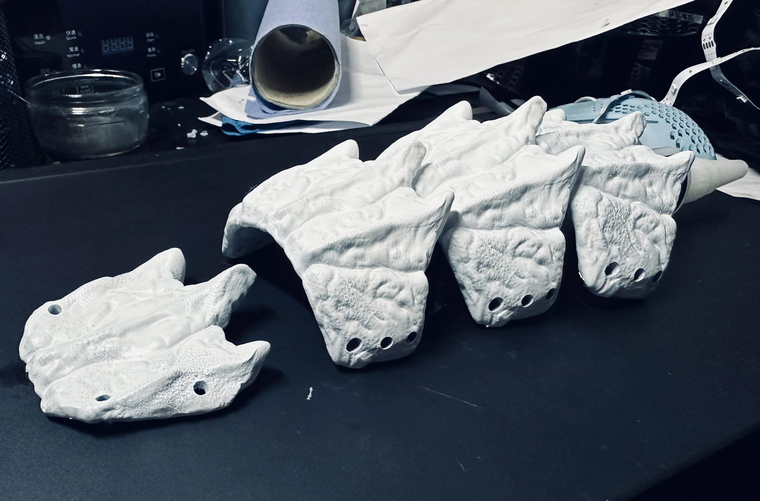 A line of several white rock climbing holds shaped like frog heads placed on a dark surface.