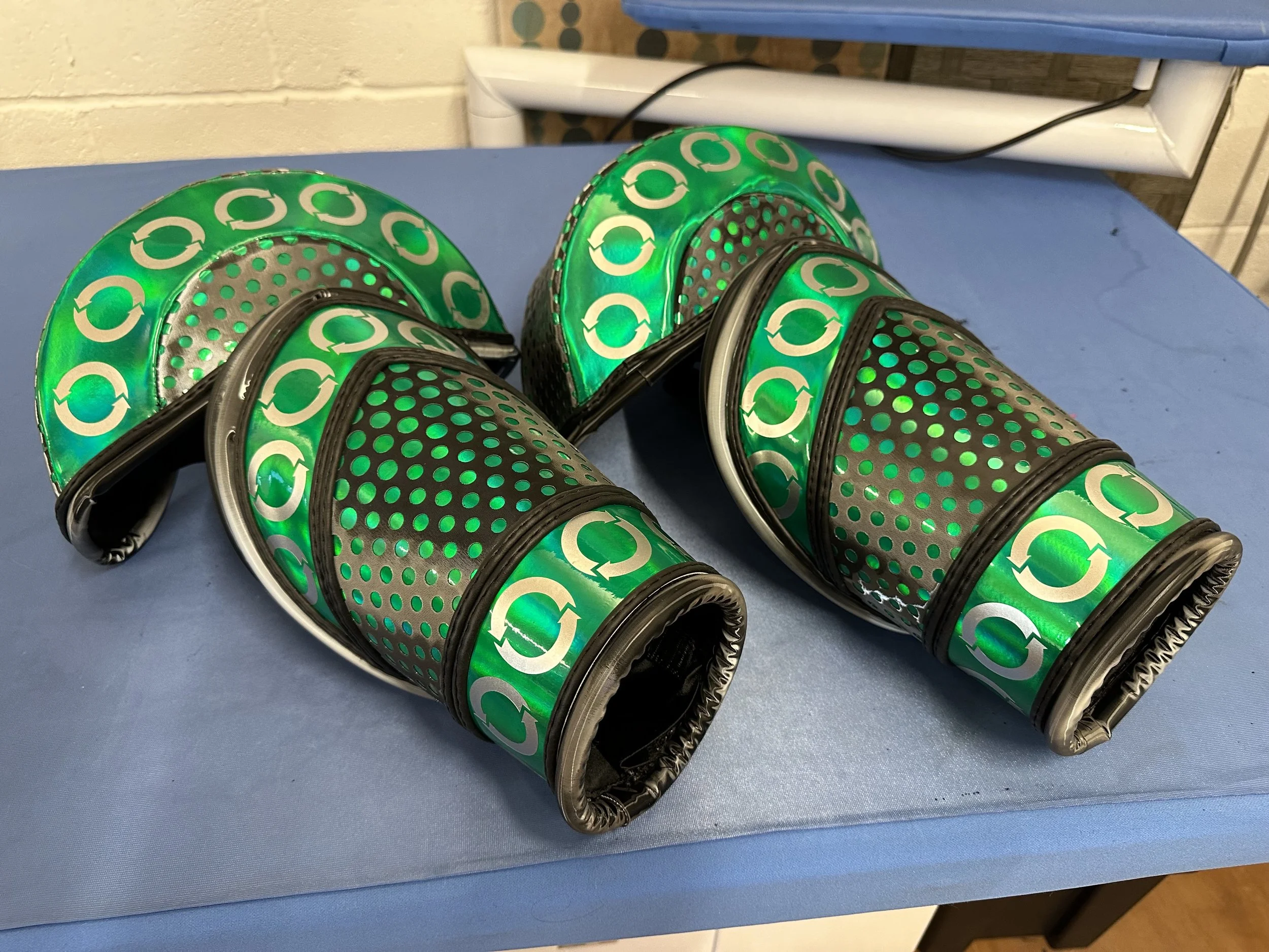 A pair of green and black headlamps with circular icons, lying on a blue table.