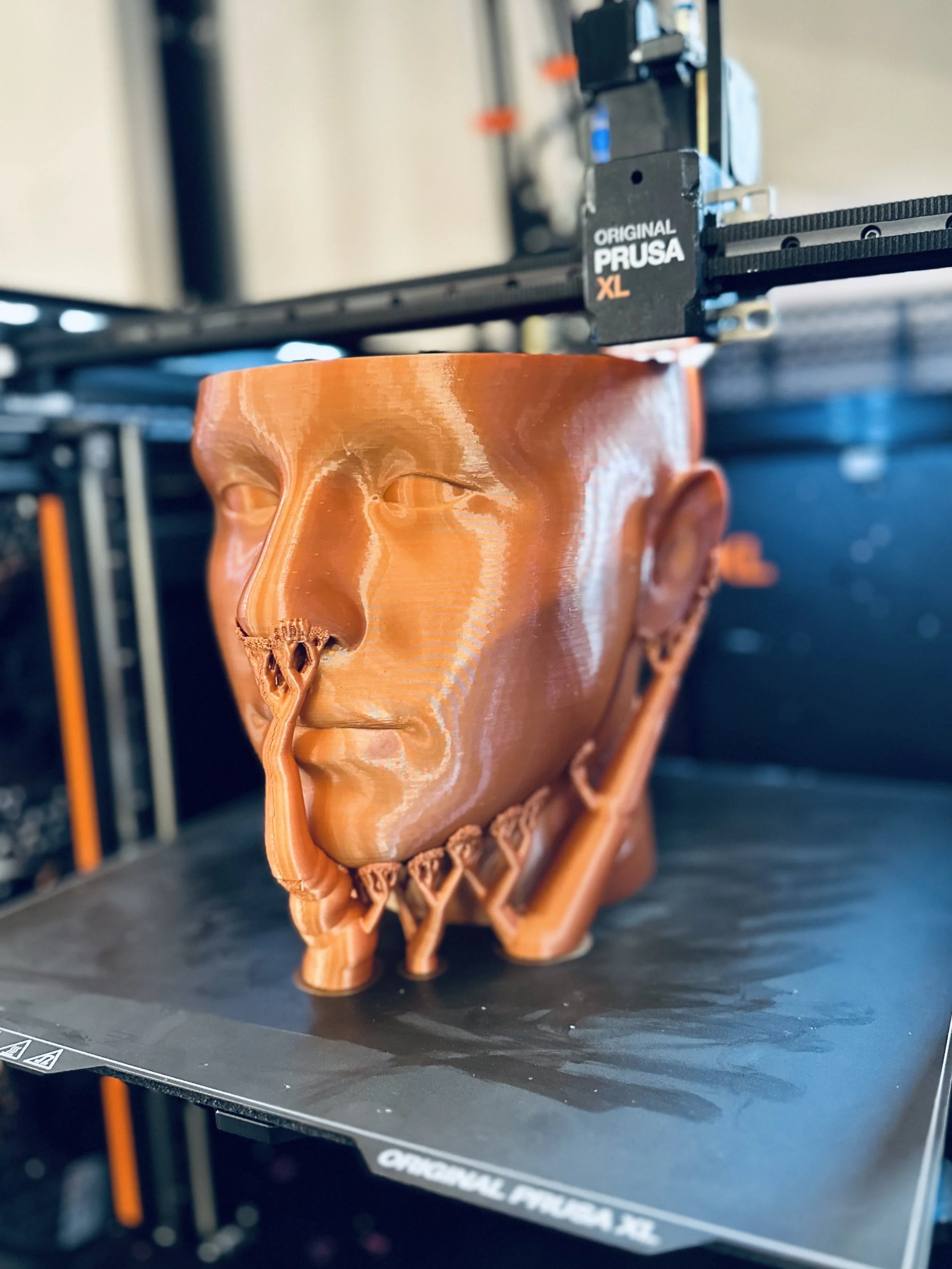 3D printed smiling human face mask on 3D printer bed.