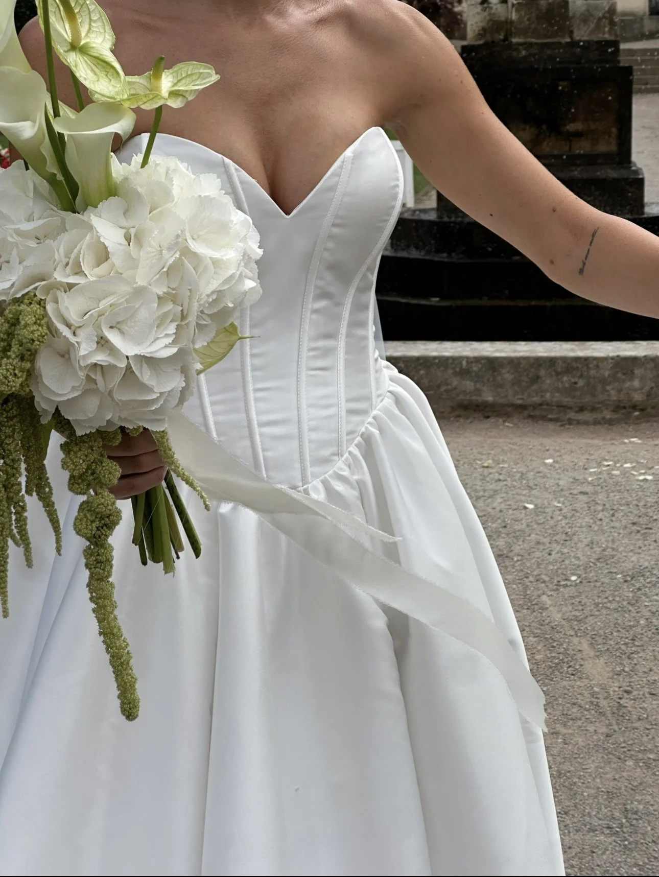 A woman in a white wedding gown holding a bouquet of white flowers.